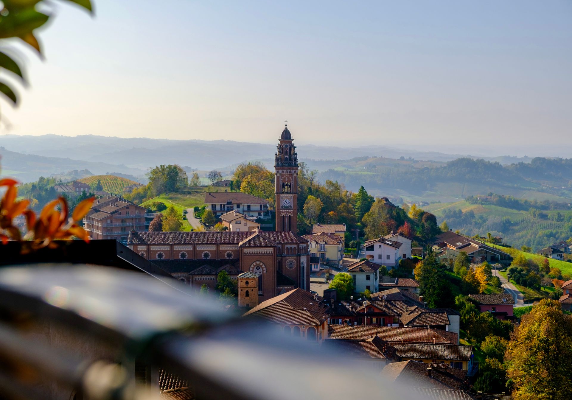 Hilltop village in Piedmont with a bell tower and autumn vineyards behind
