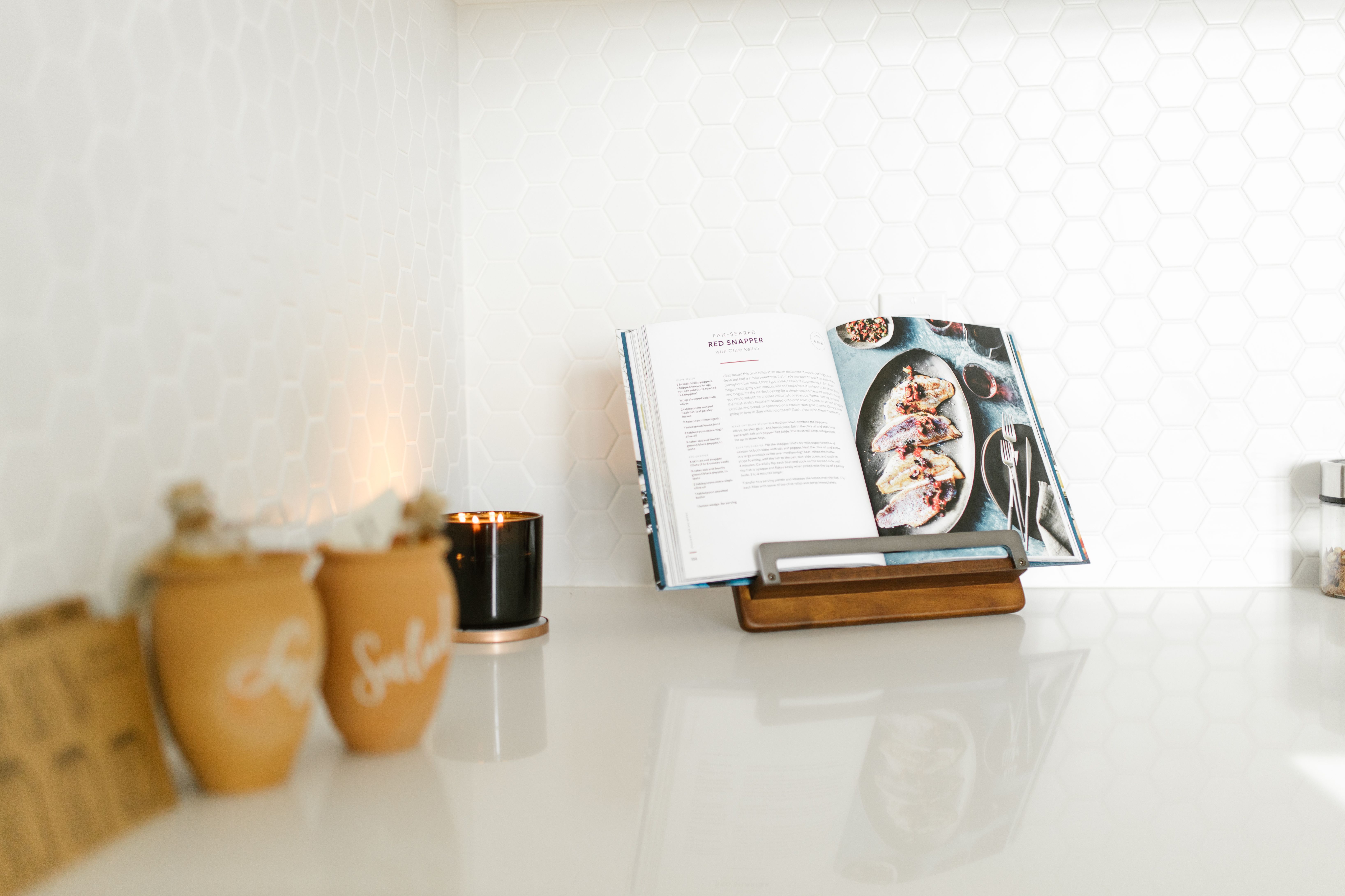 An open cookbook on a wooden stand on a kitchen counter