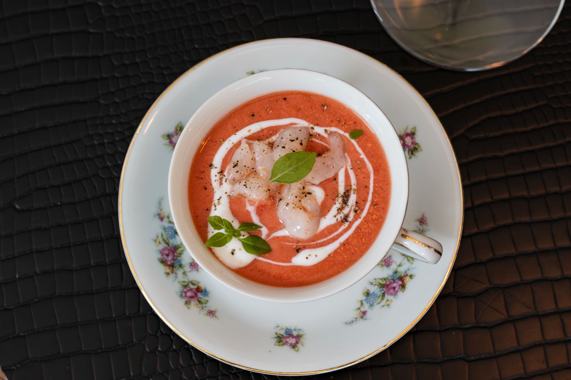 Bowl of chilled red gazpacho soup swirled with cream and basil