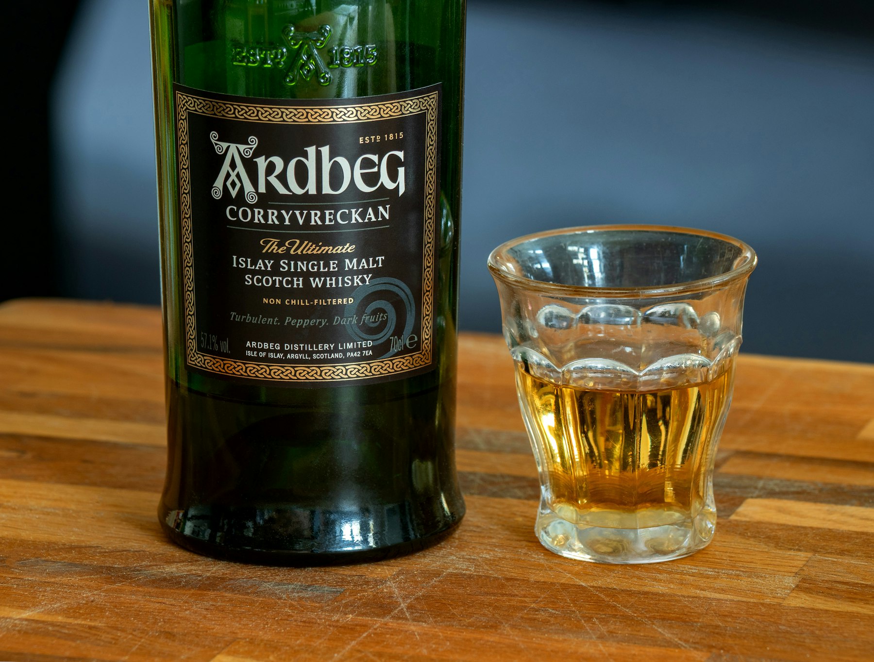 Fles Ardbeg Islay single malt Schotse whisky naast een gevuld glas op een houten bar