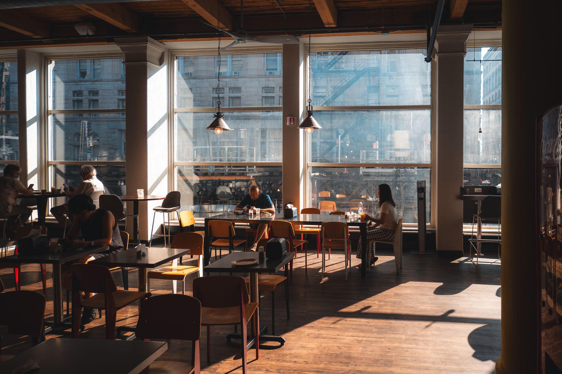 Diners at wooden tables in a sunlit restaurant dining room