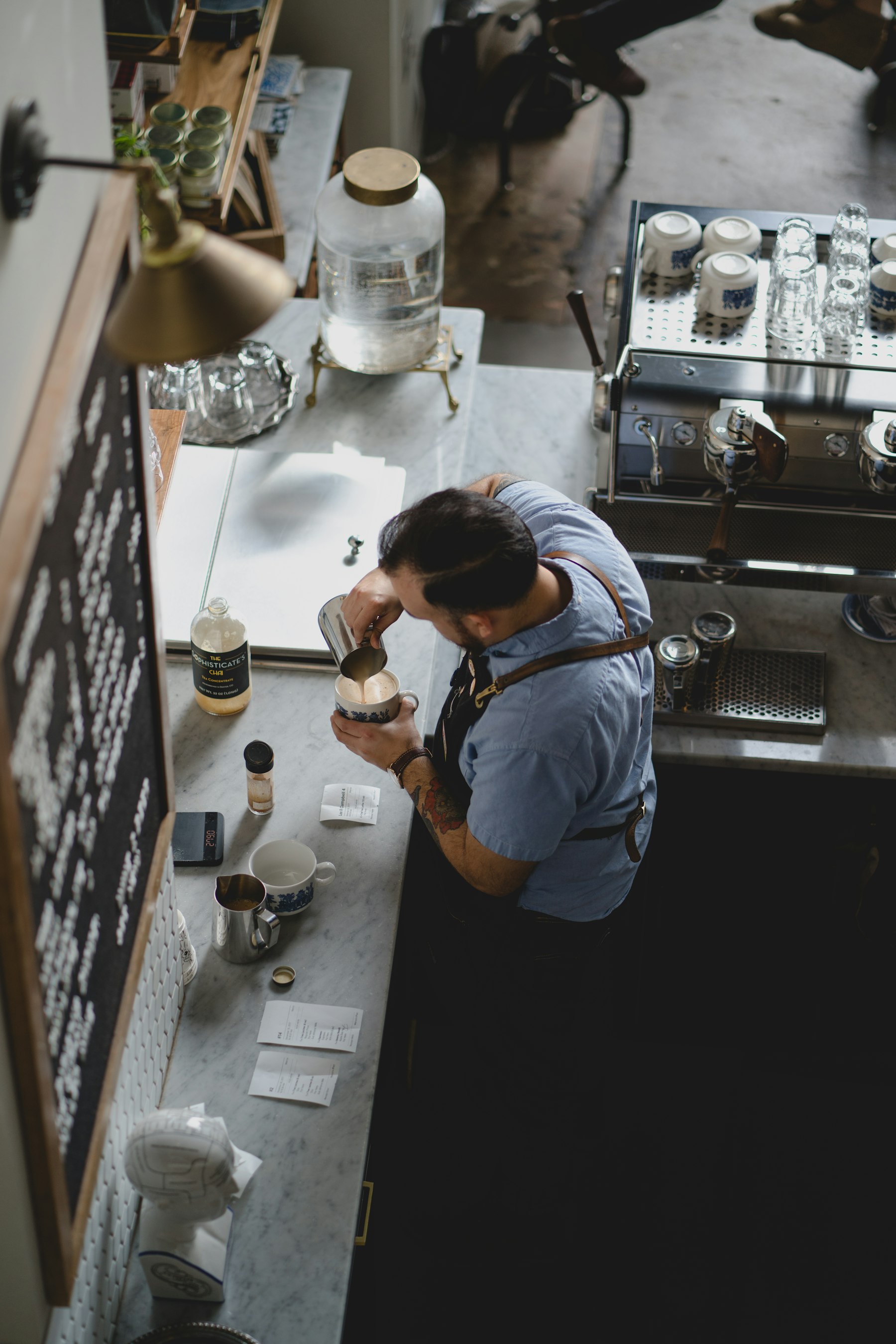 Un barista versa latte montato in una tazza da espresso su un bancone di marmo