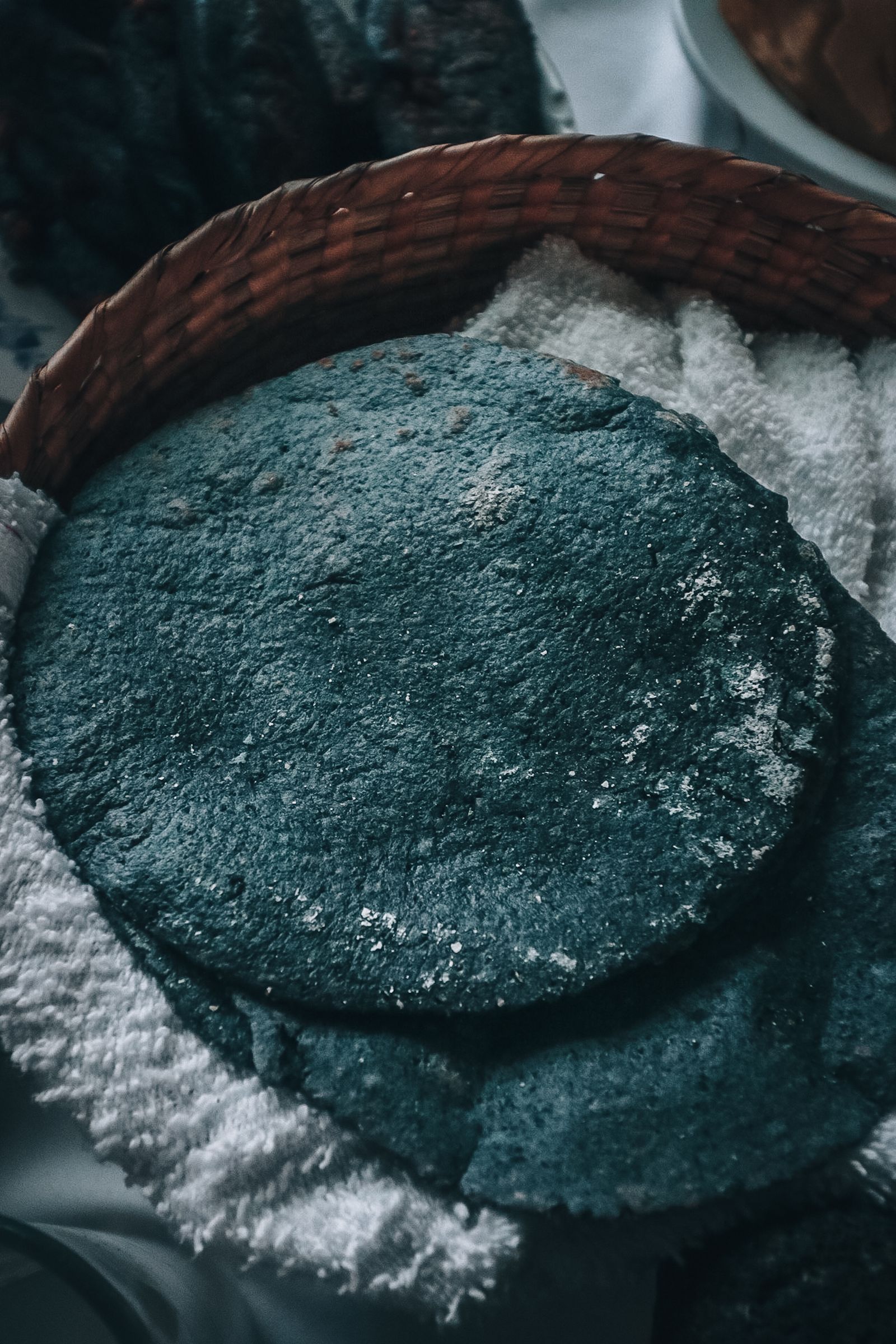 Stack of blue corn tortillas in a woven basket lined with cloth