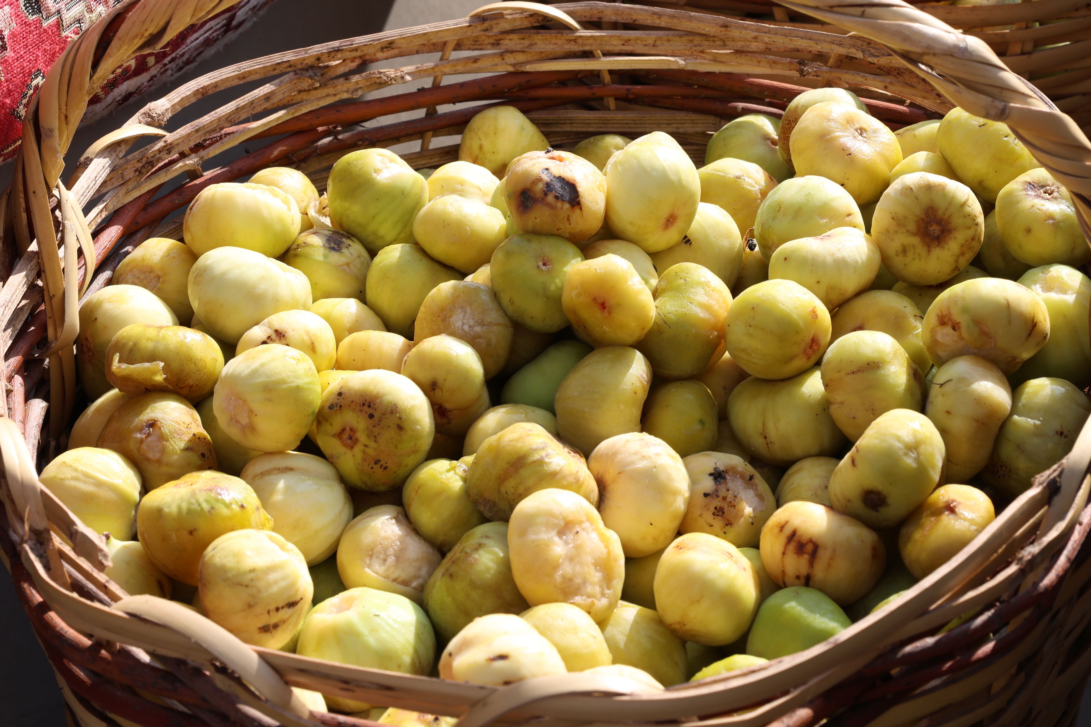 Basket overflowing with fresh green figs at a market stall