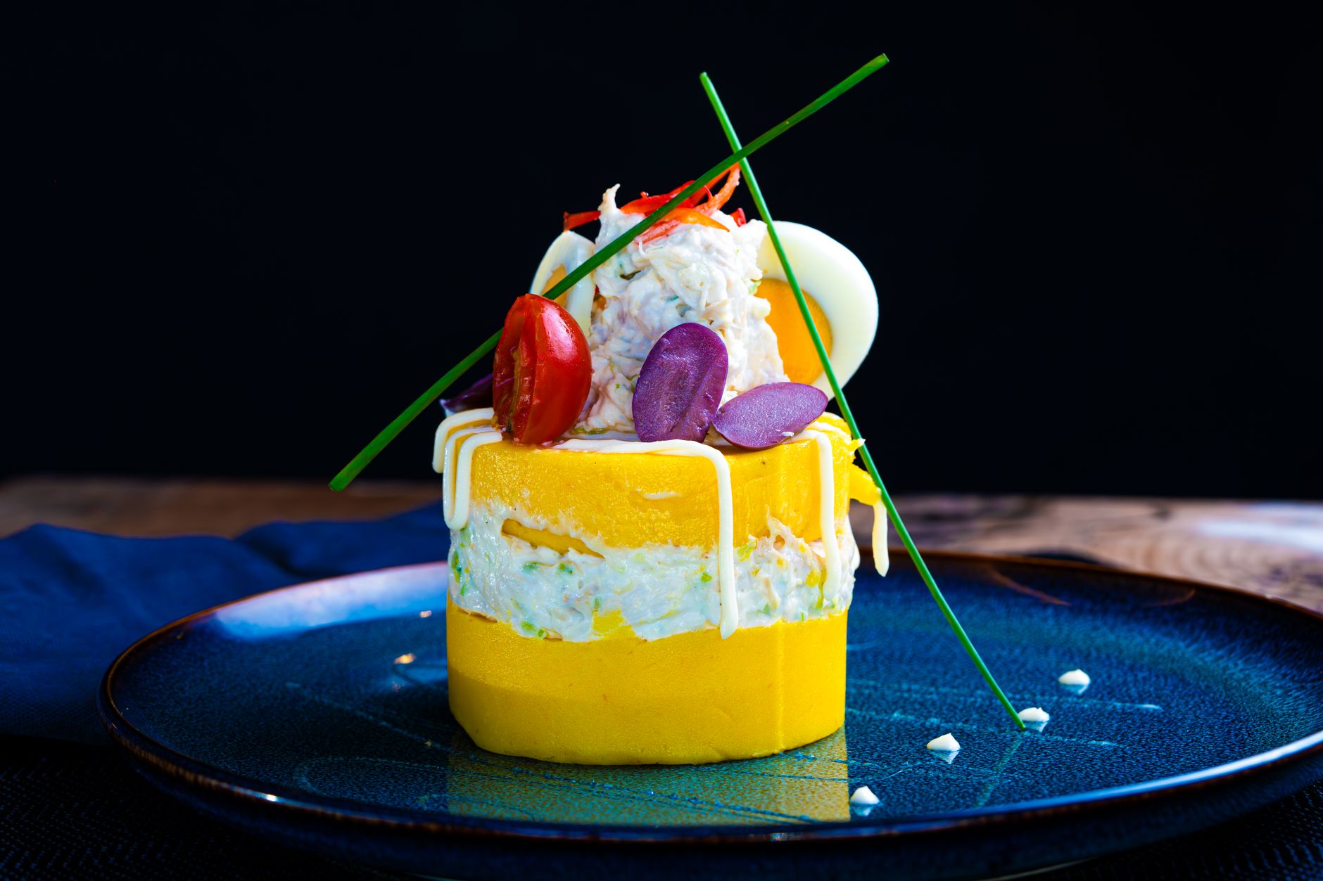 Une causa limeña en couches de pomme de terre jaune avec salade de poulet, œuf et tomate