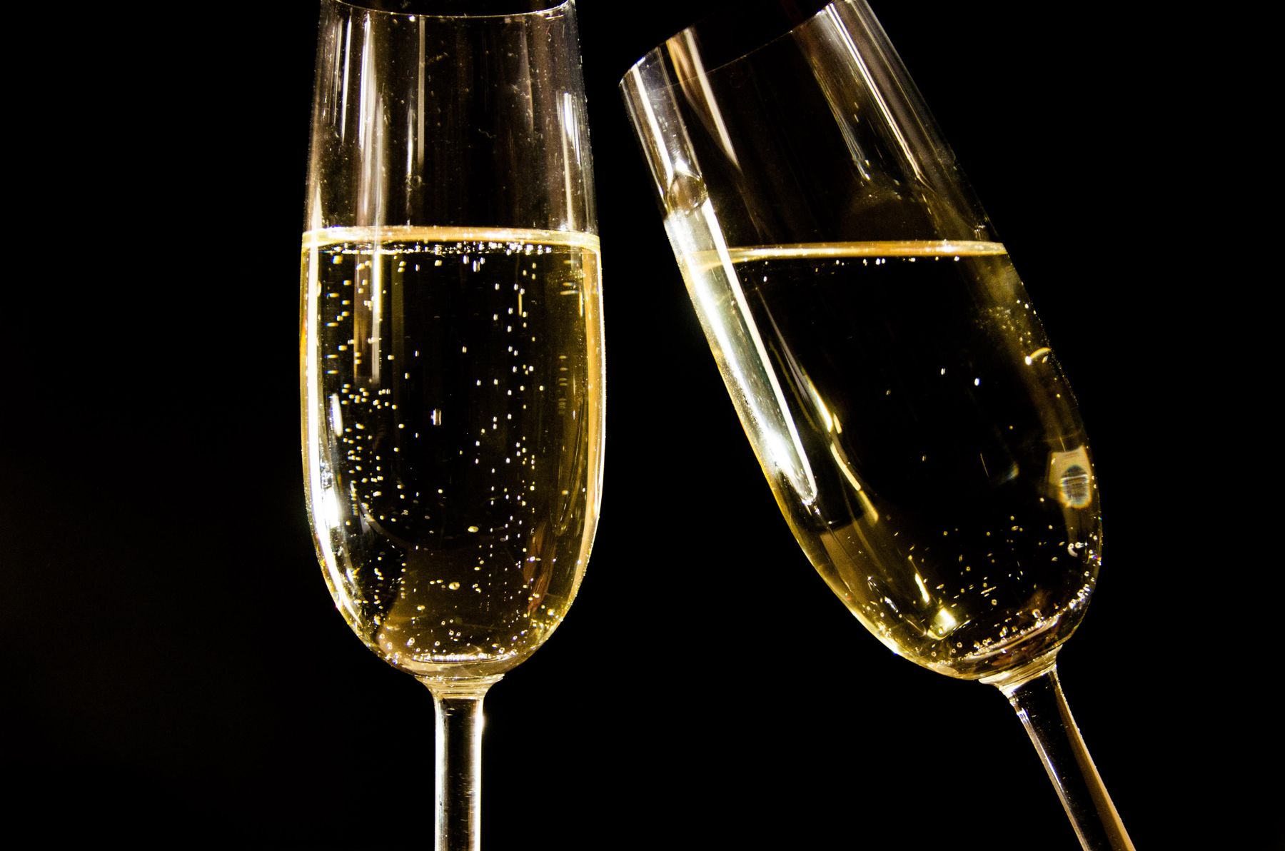 Close-up of two champagne flutes filled with sparkling wine against a dark background
