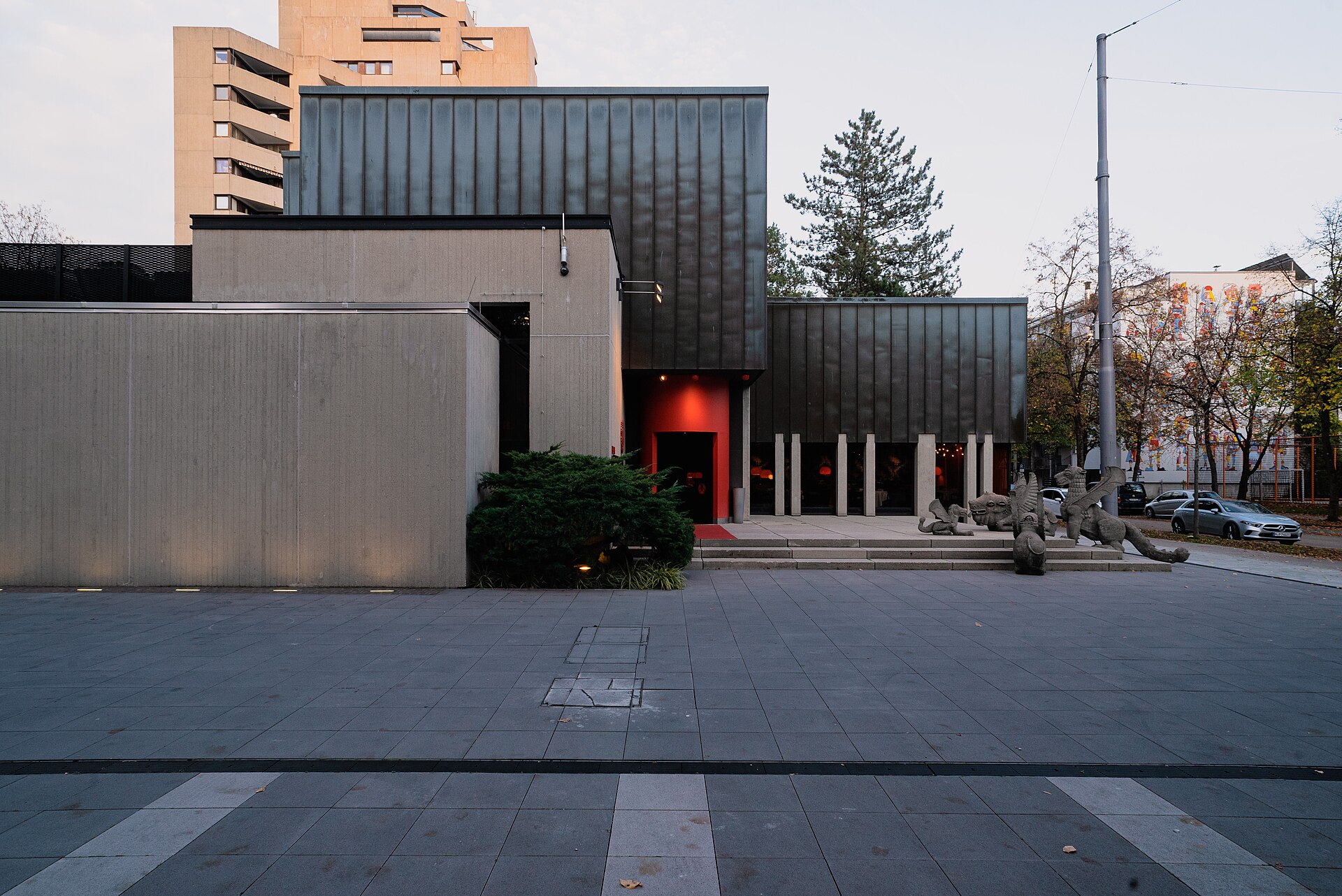 Concrete and dark metal facade of Tantris restaurant in Munich with red entrance