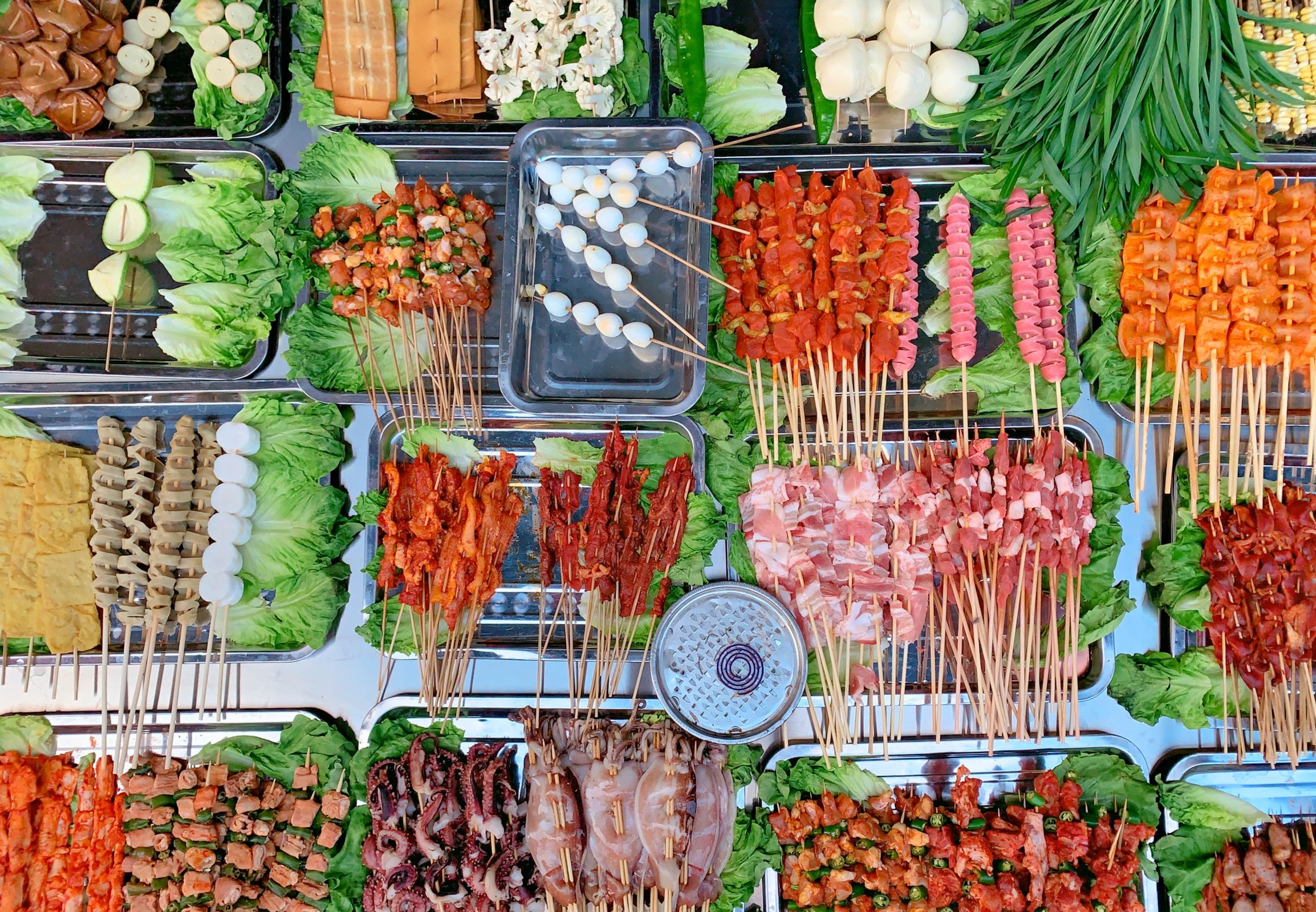 Reihen roher Fleisch-, Tofu- und Gemüsespieße auf einem Streetfood-Stand in Chengdu