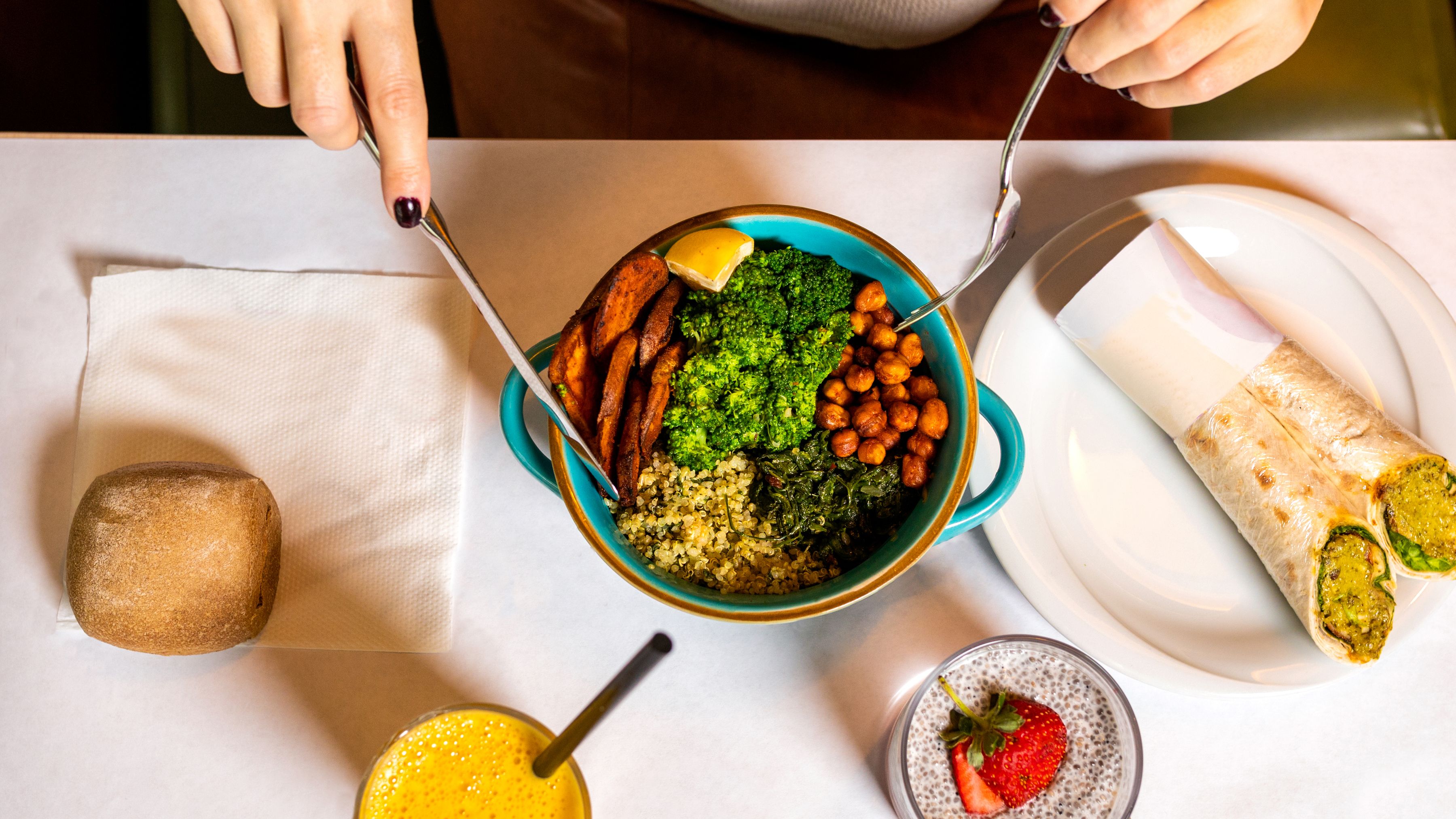 Overhead view of a burrito bowl and wrap on a restaurant table