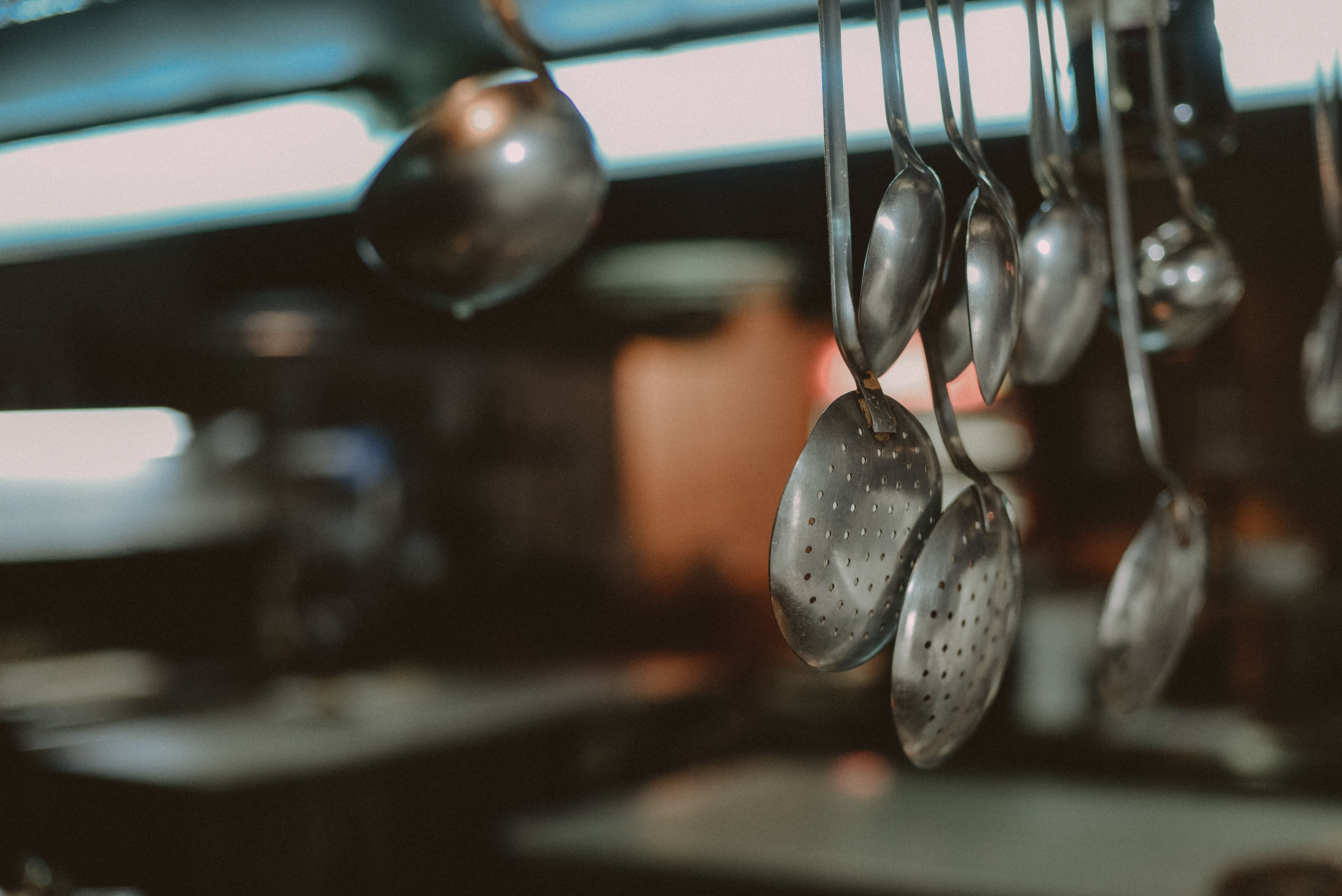 Ladles and skimmers hanging above a restaurant kitchen line