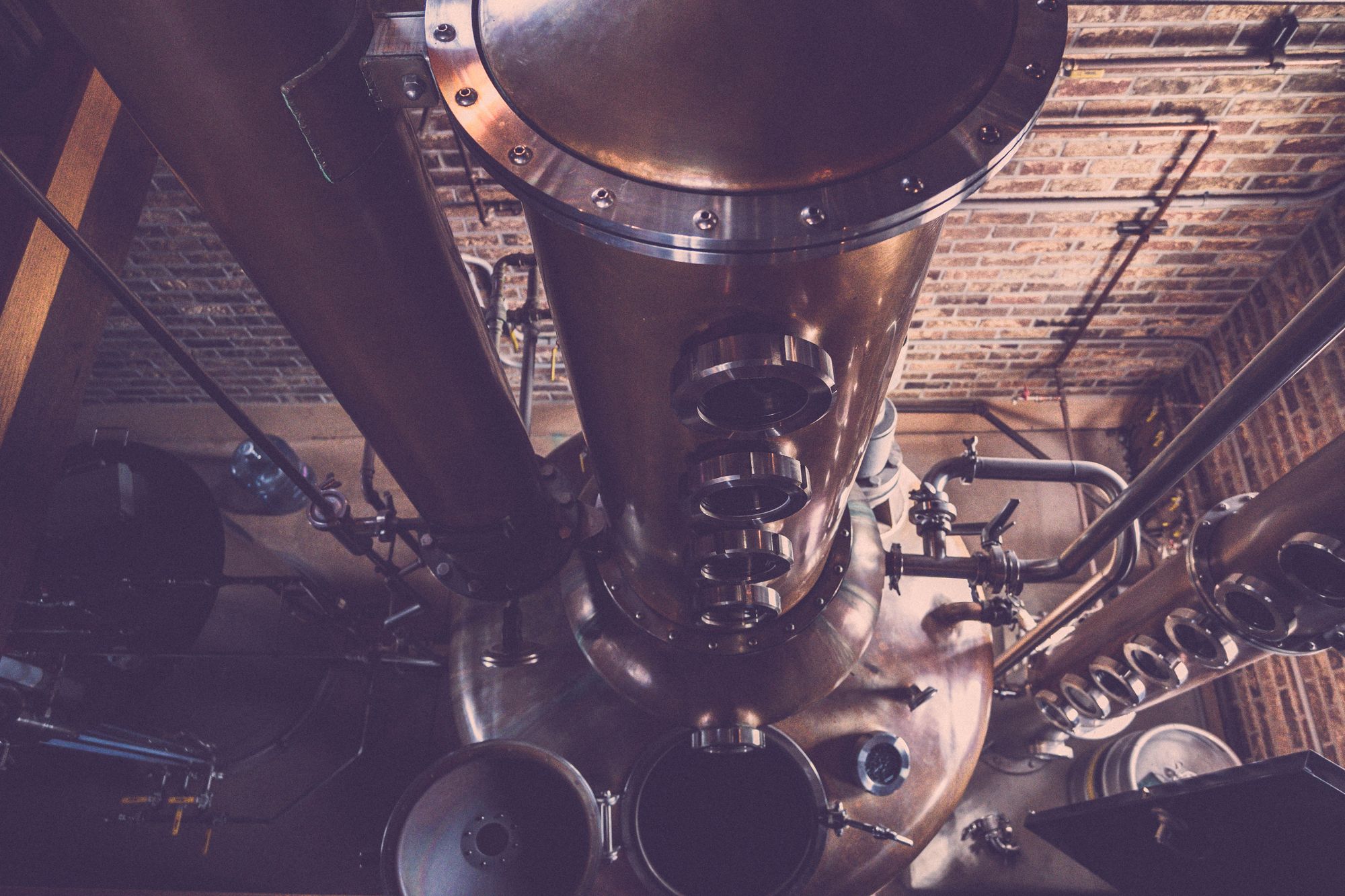 Alambicco di rame e colonna di distillazione in una distilleria di mattoni, senza persone