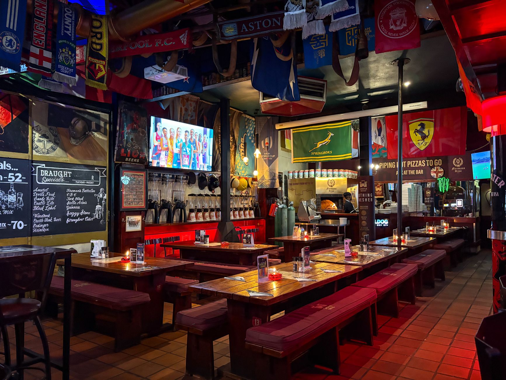 Una sala di uno sports bar con tavoli riservati, schermi e scaffali di spine per birra