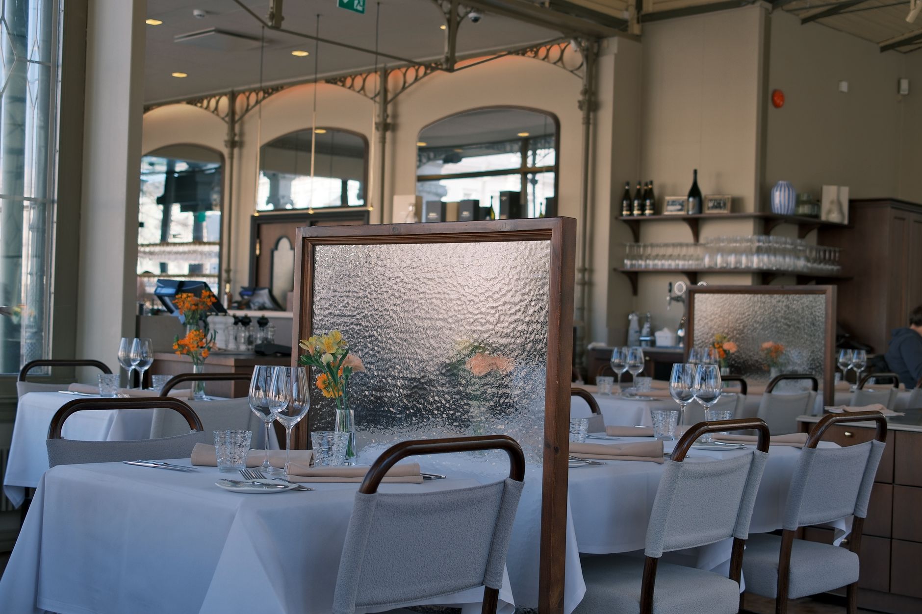 Tables dressées de linge blanc, de verres à vin et de fleurs fraîches dans une salle à manger élégante
