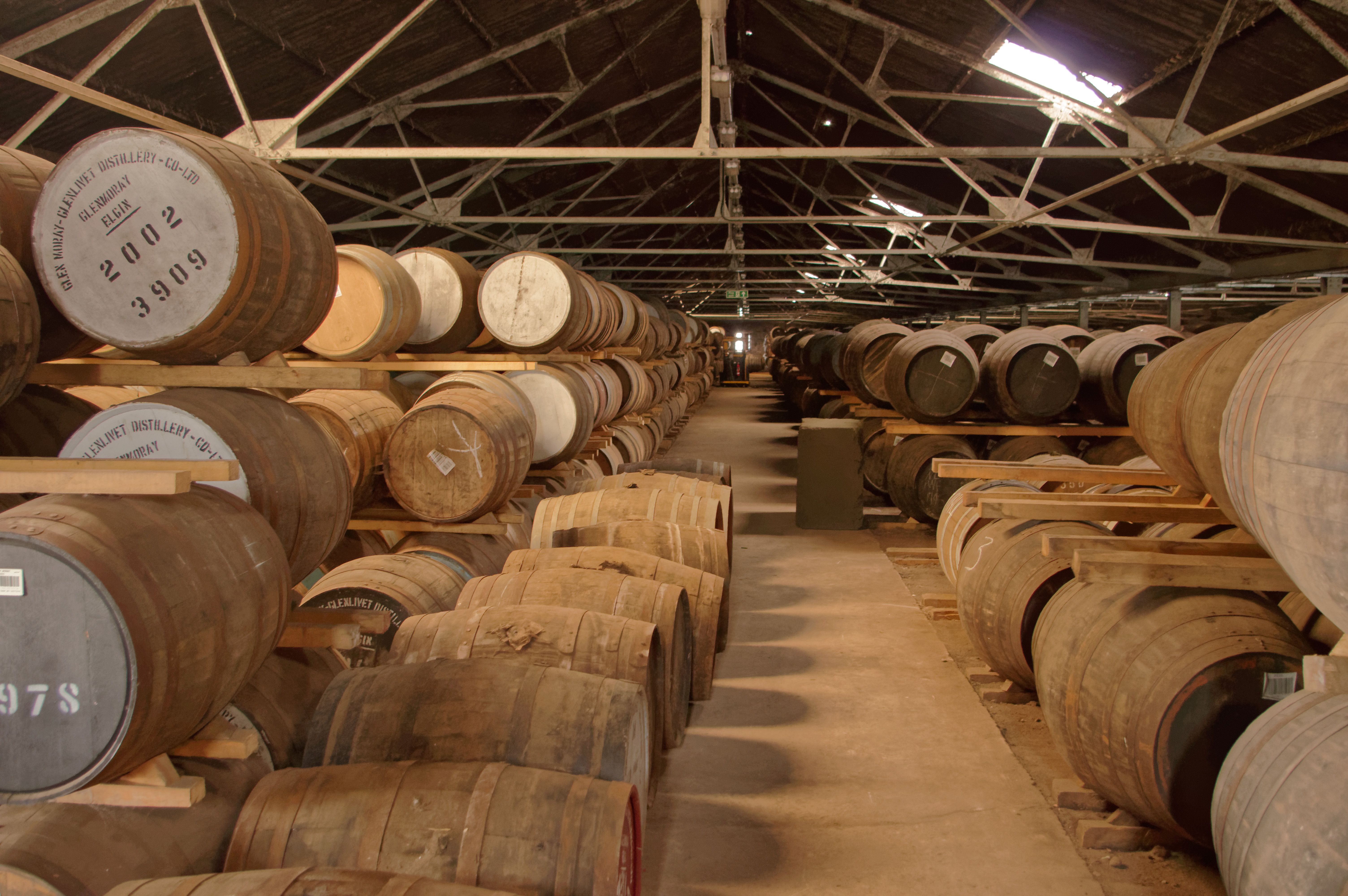 Rows of oak whisky barrels ageing in a distillery warehouse