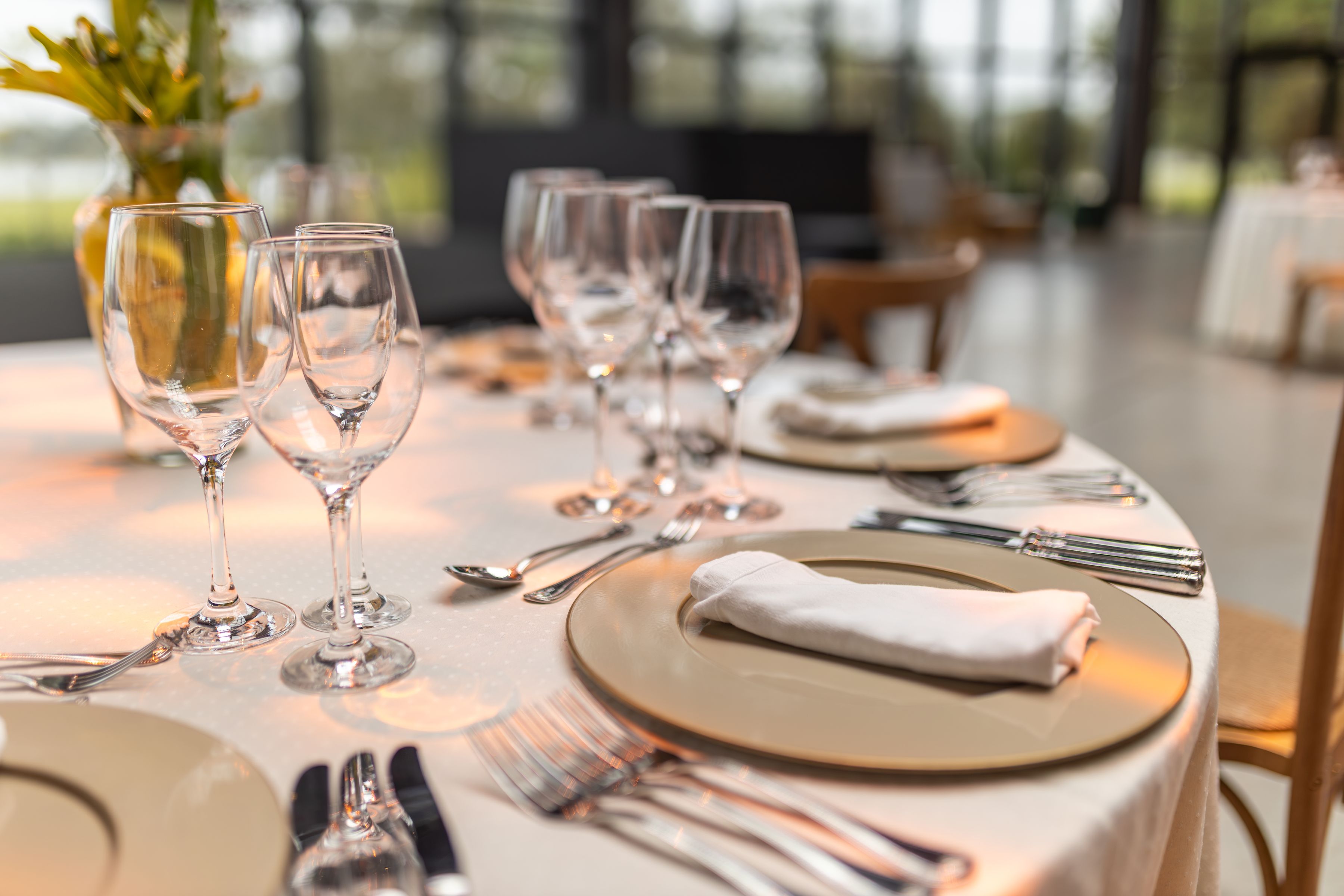 A round table set with wine glasses and linen napkins in an elegant restaurant