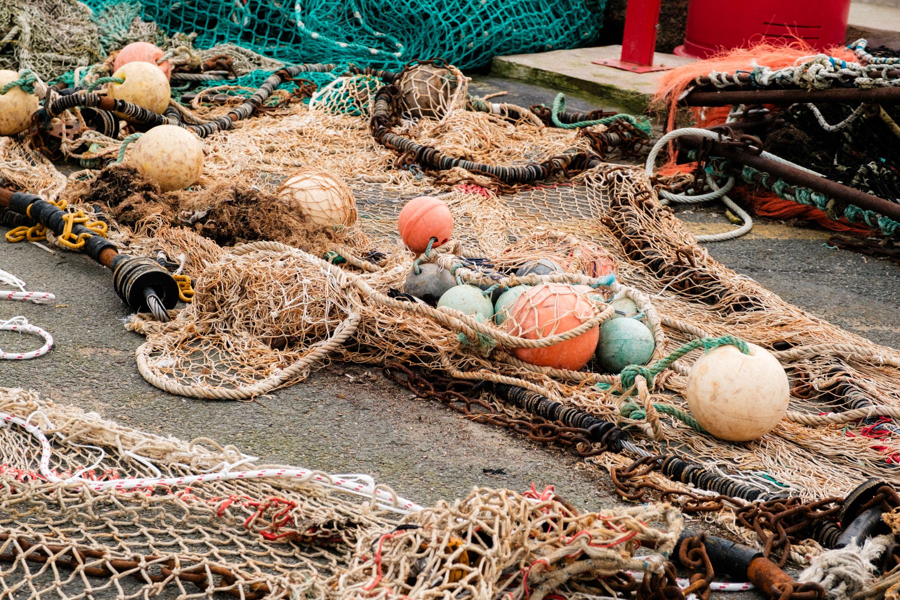 Filets de chalut, flotteurs et chaîne étalés sur un quai