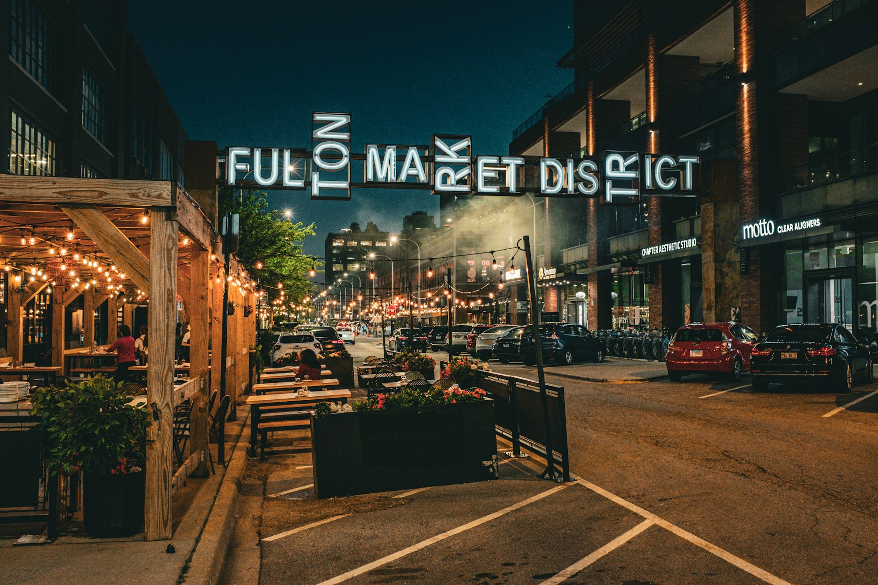 Fulton Market District sign glowing above a Chicago restaurant street at night