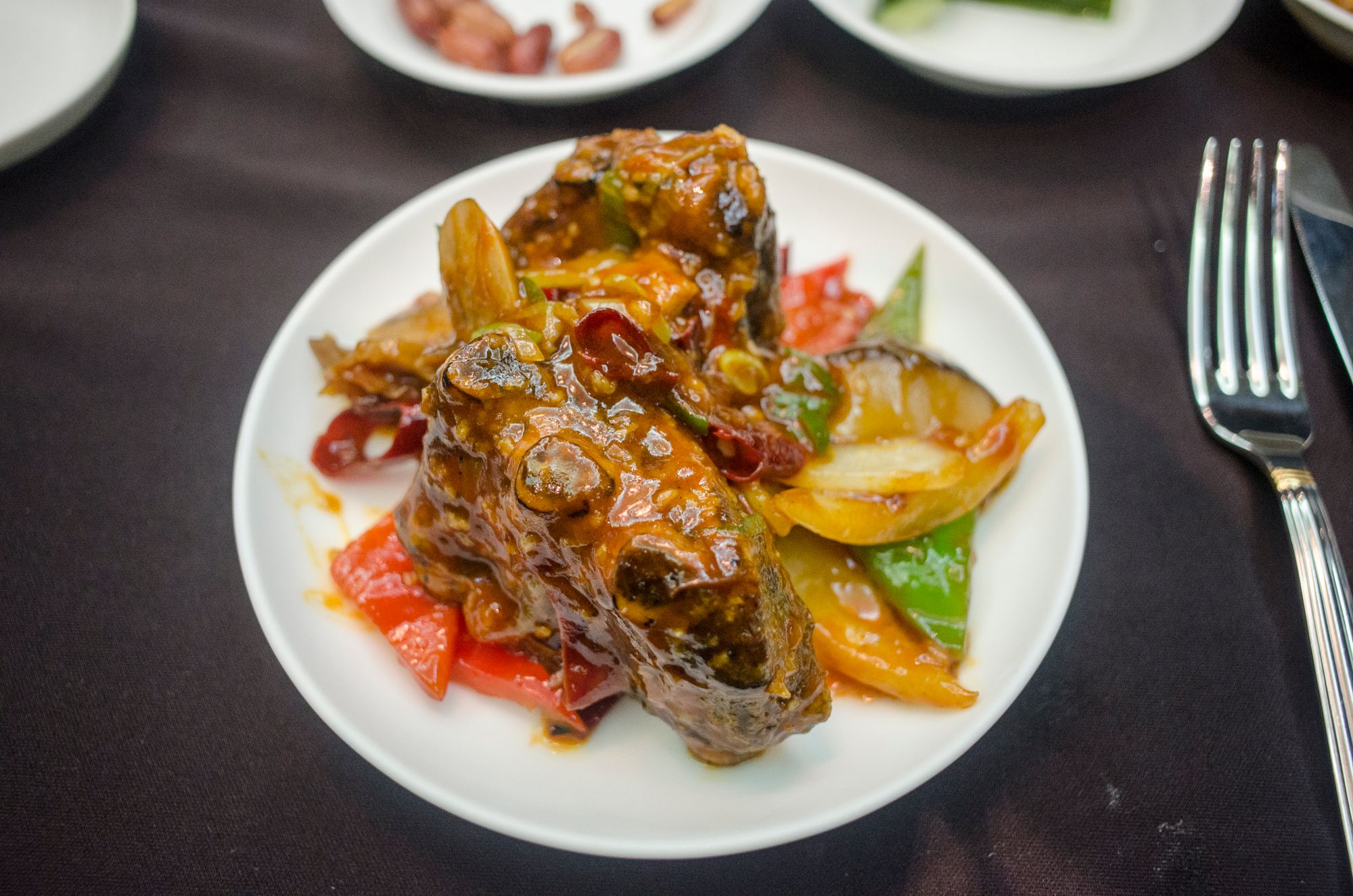 Glazed braised beef short rib with peppers and onion on a white plate