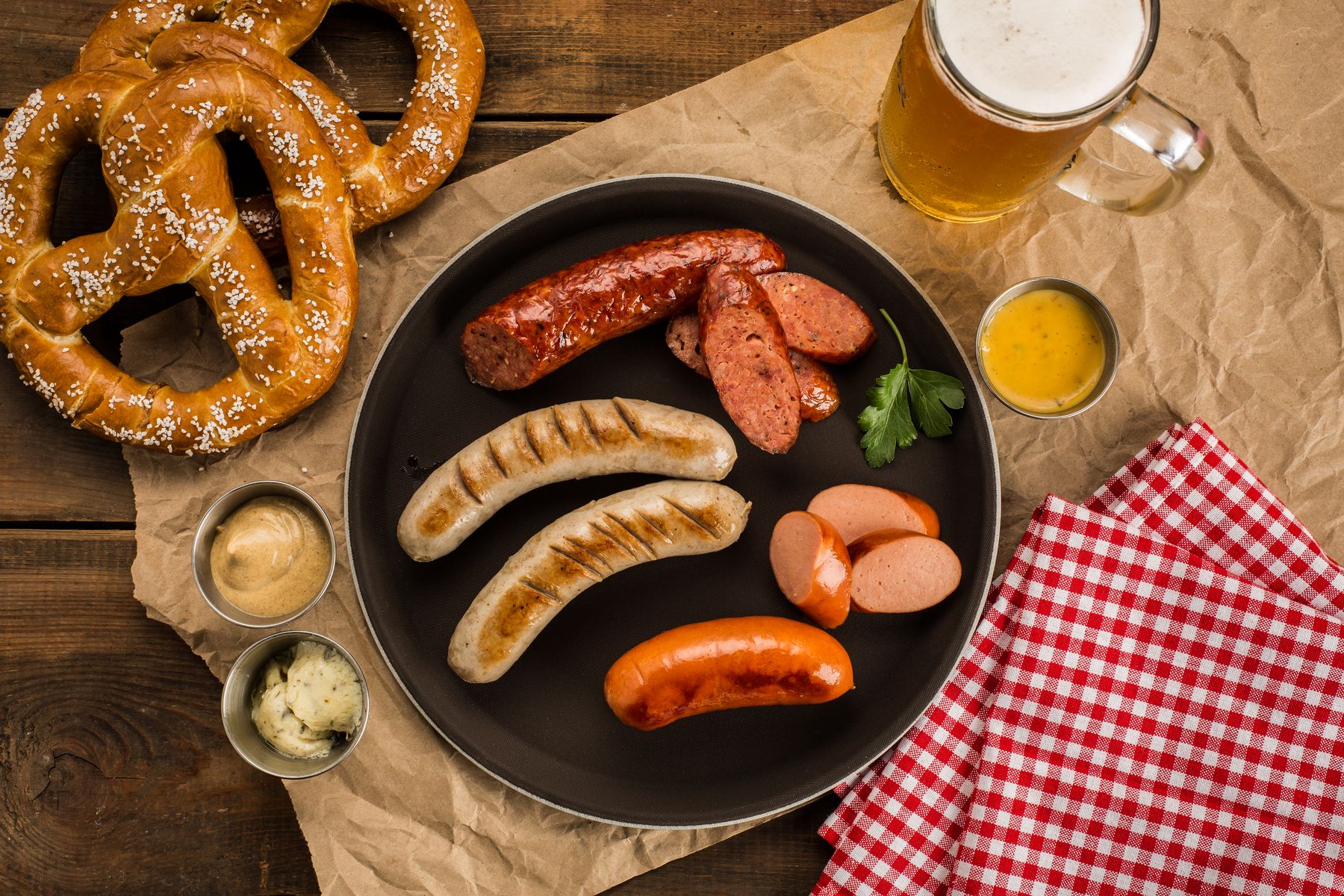 Grilled German sausages, pretzels, mustard and beer arranged on a wooden table