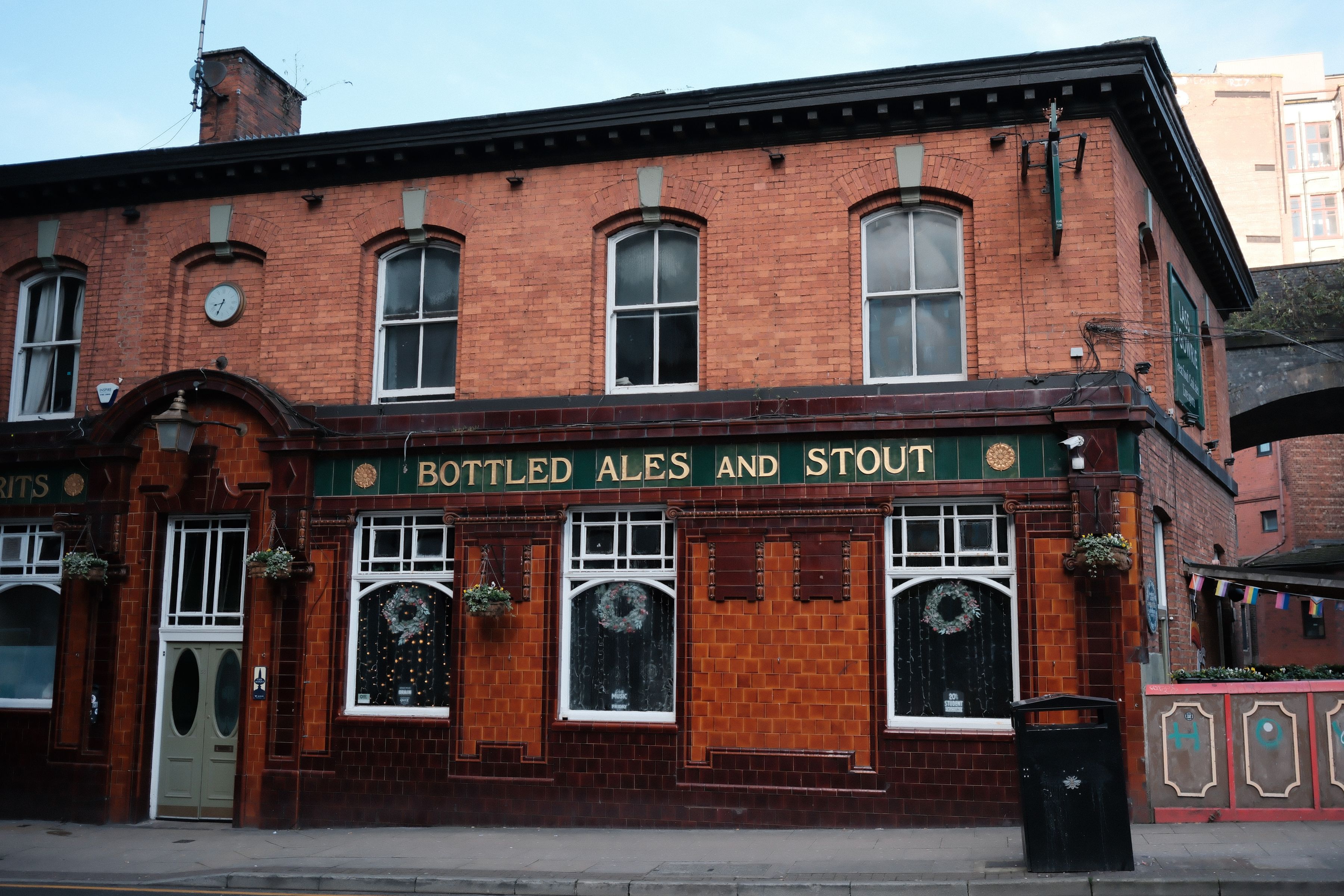 Historic red brick British pub facade with tiled ale and stout signage