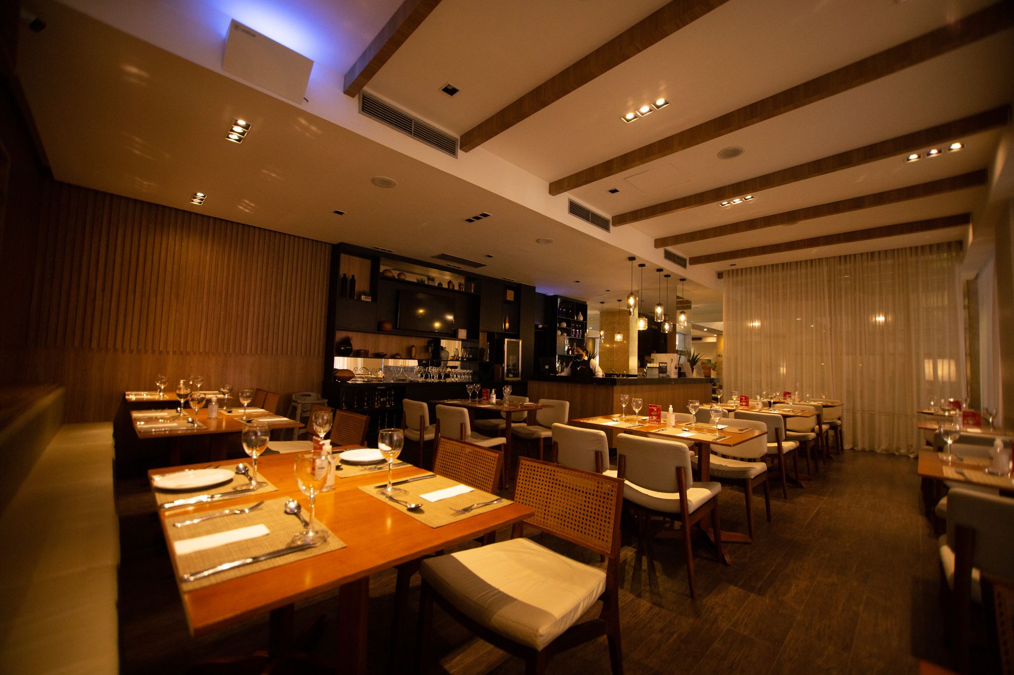Tables laid with glasses and cutlery in an empty restaurant dining room before service