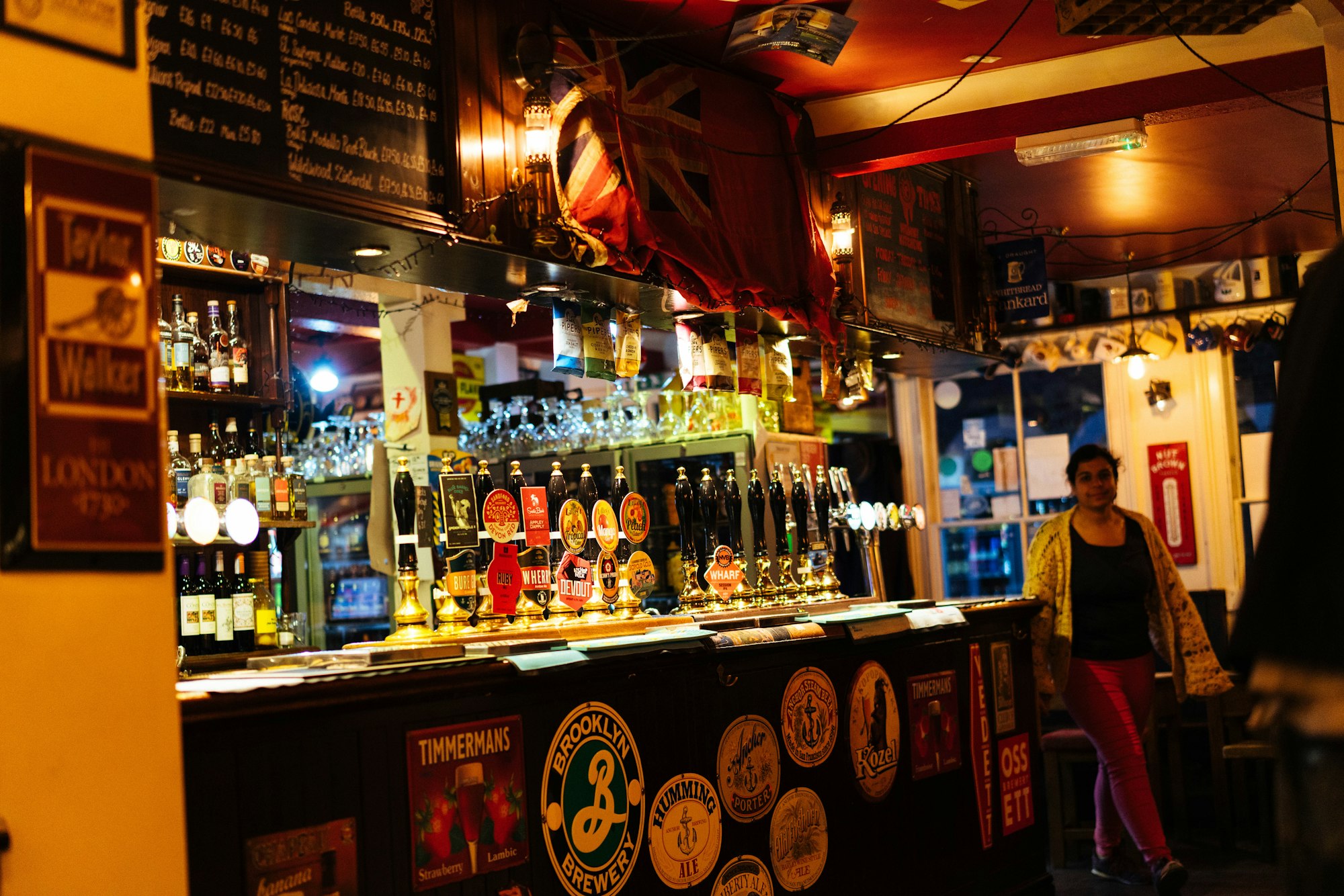 Busy London pub bar with beer taps, bottles and a Union Jack overhead