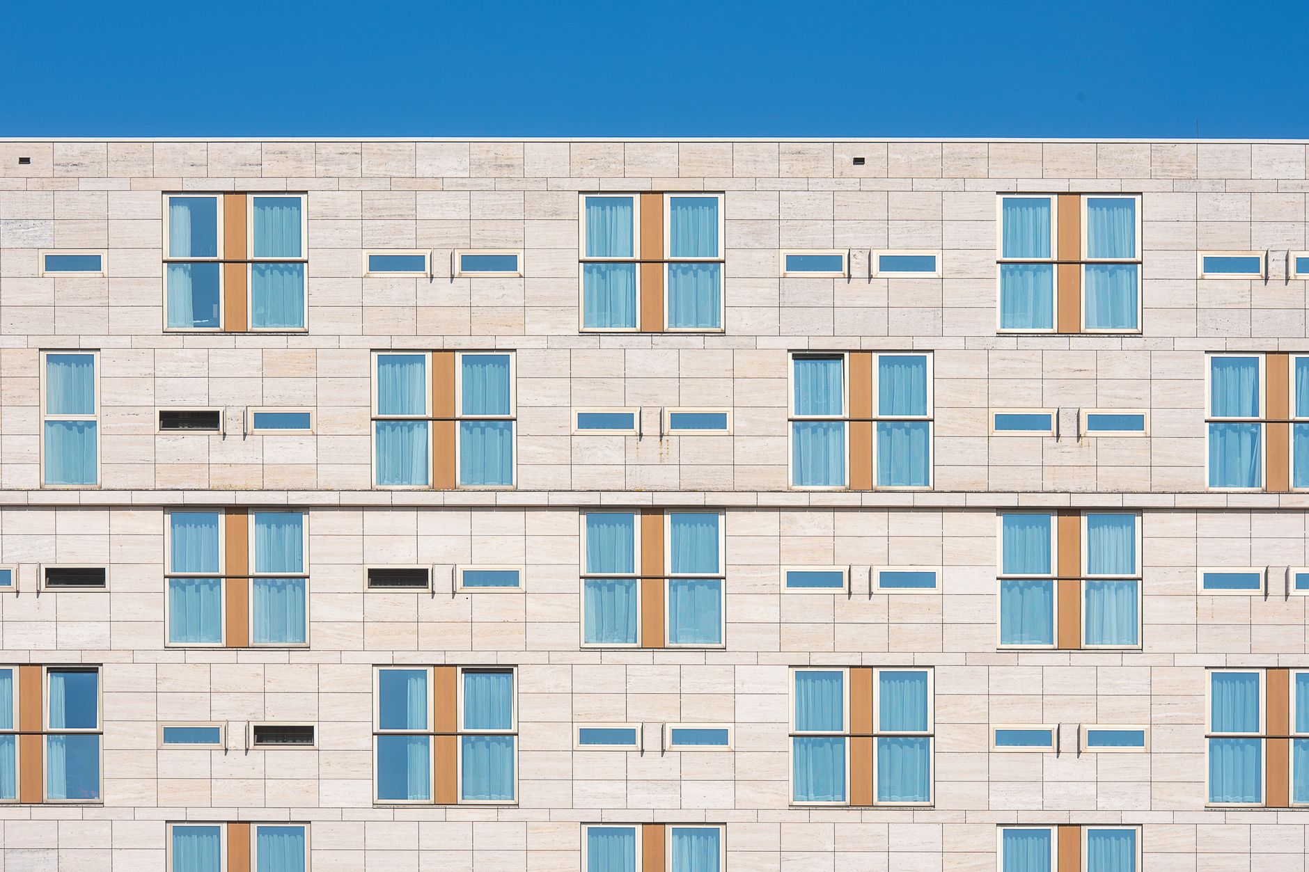 Modern hotel facade with rows of windows under a clear sky