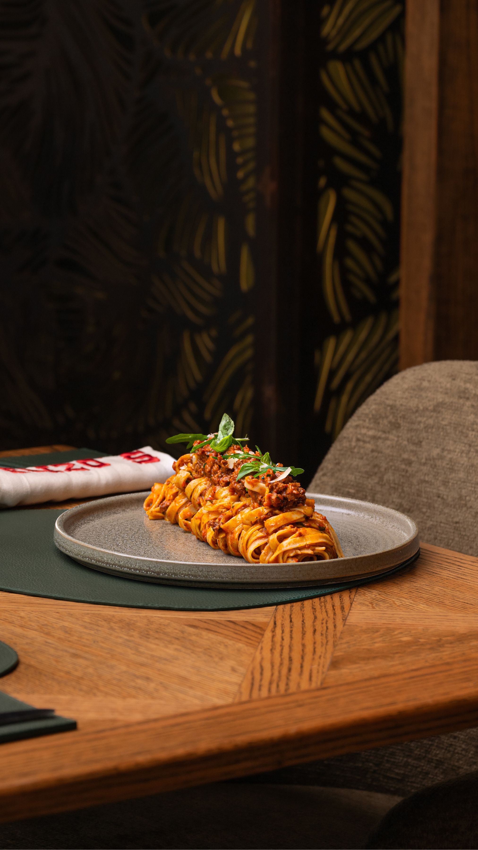 A plated tagliatelle dish with sauce and herbs on a table in an elegant restaurant