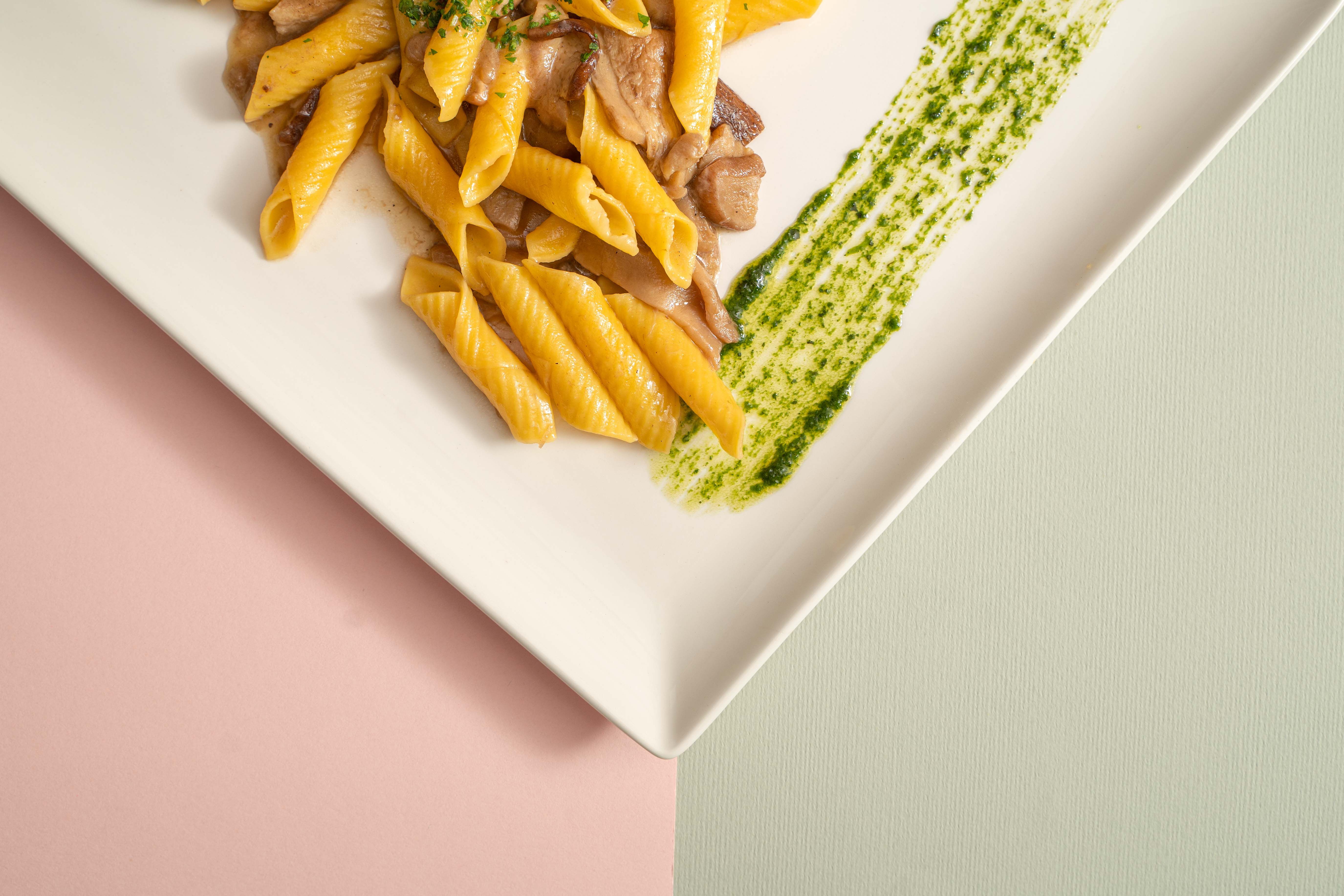 Plated pasta dish with a bright green herb sauce on a modern white plate