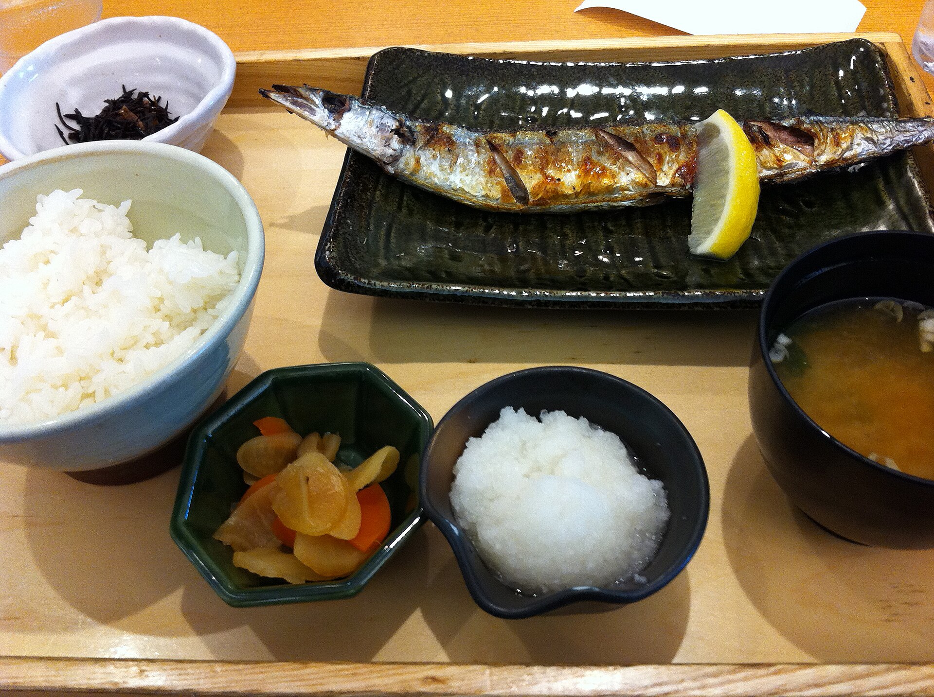 Grilled Pacific saury with lemon, grated daikon, rice and miso soup on a tray