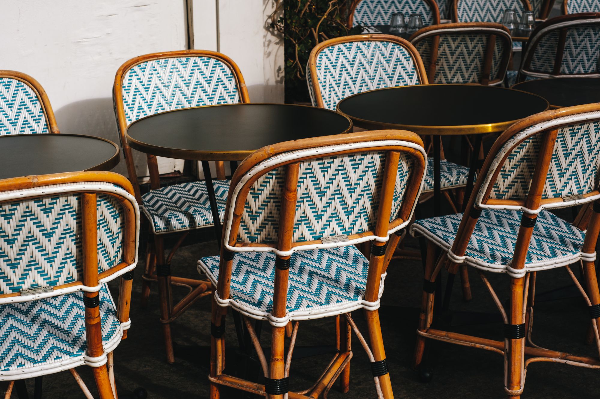 Rattan bistro chairs and small round tables lined up on a terrace