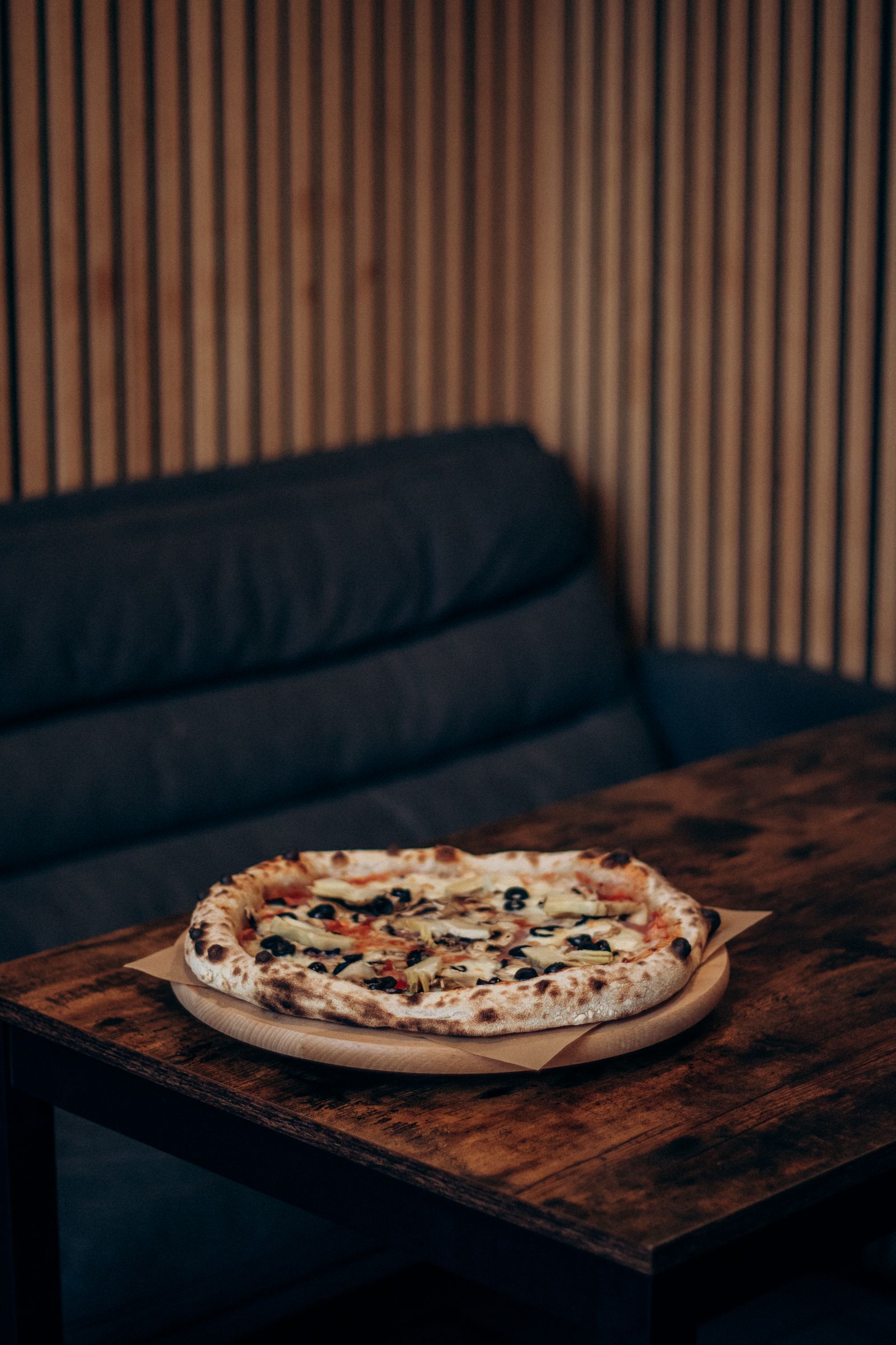 A wood-fired Neapolitan-style pizza served on a wooden table in a cosy Italian restaurant