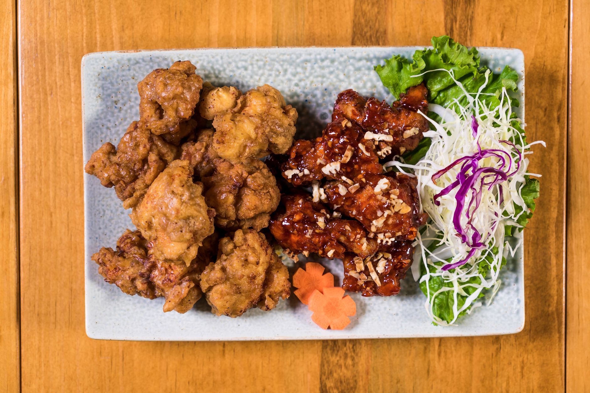 Pezzi di pollo fritto coreano dorati e glassati serviti con lattuga e verdure sottaceto