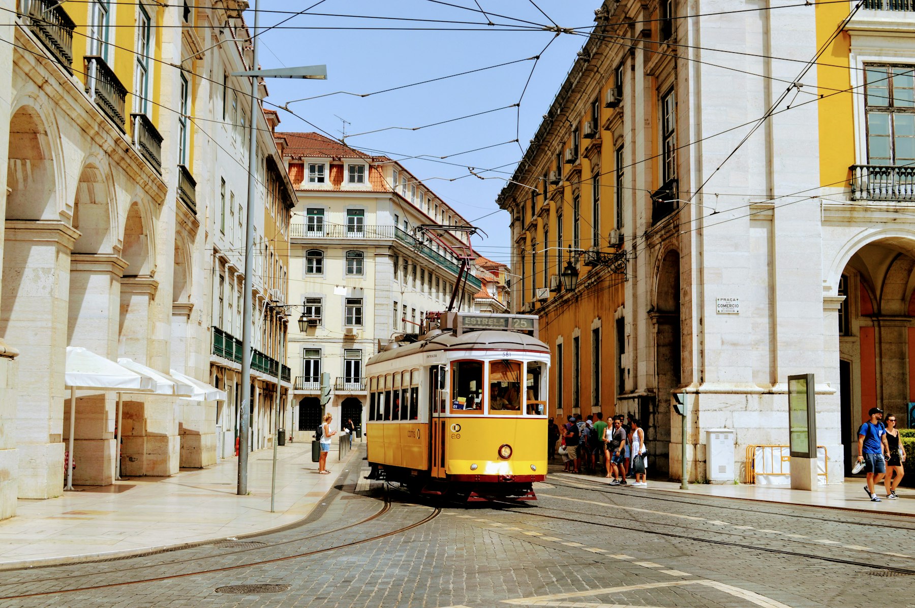 A yellow Lisbon tram passing through the Baixa district near Praca do Comercio