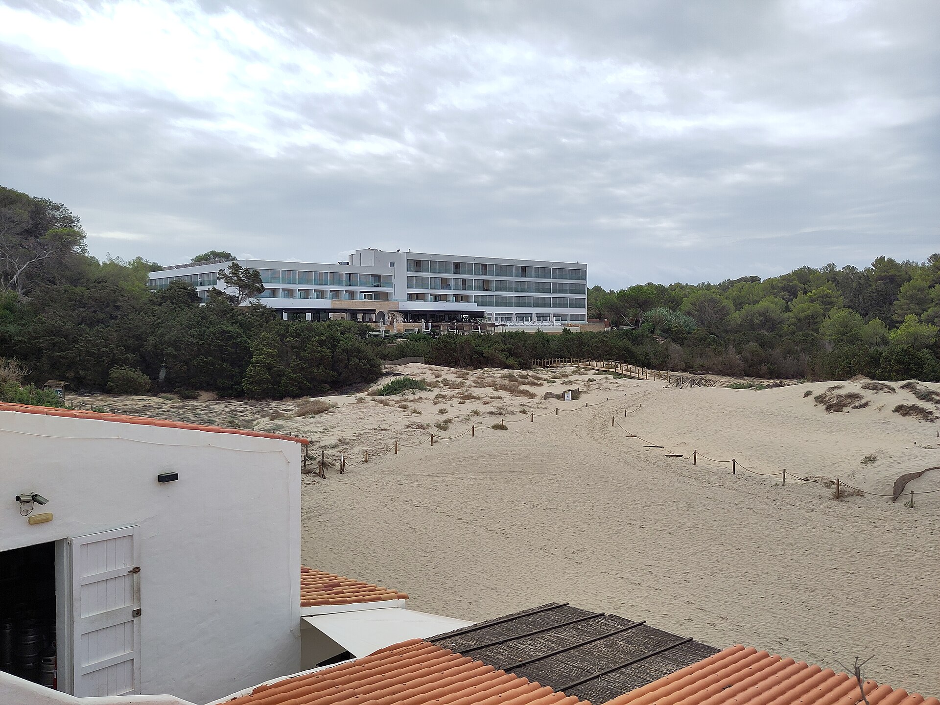 Edificio blanco de hotel sobre las dunas y el pinar de Cala Saona, Formentera