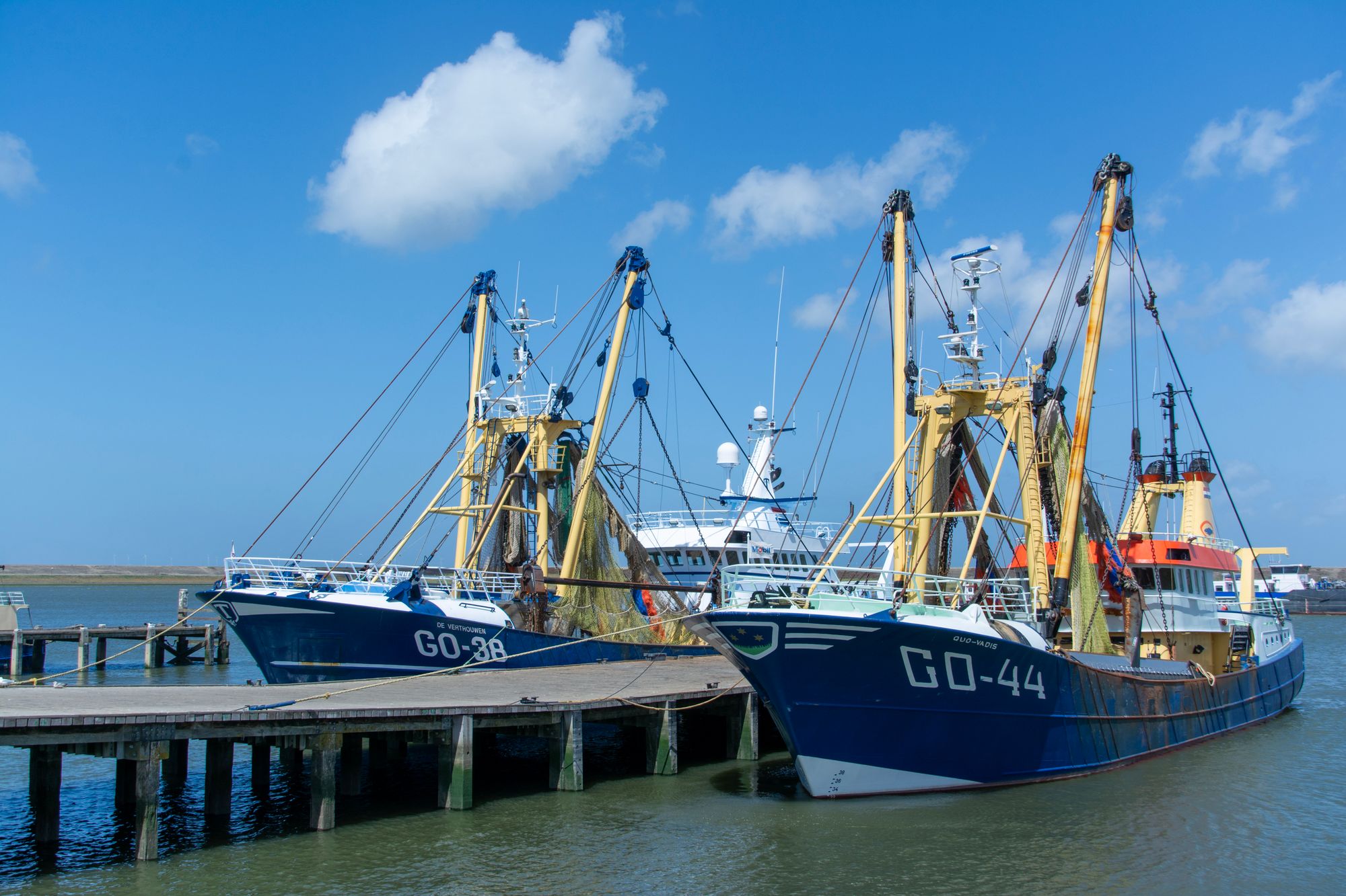 Two Dutch beam trawlers moored at Stellendam harbour under a clear sky