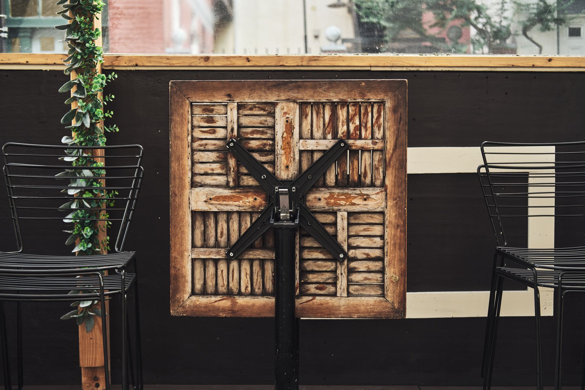 Folded wooden table and empty metal chairs on a closed cafe terrace