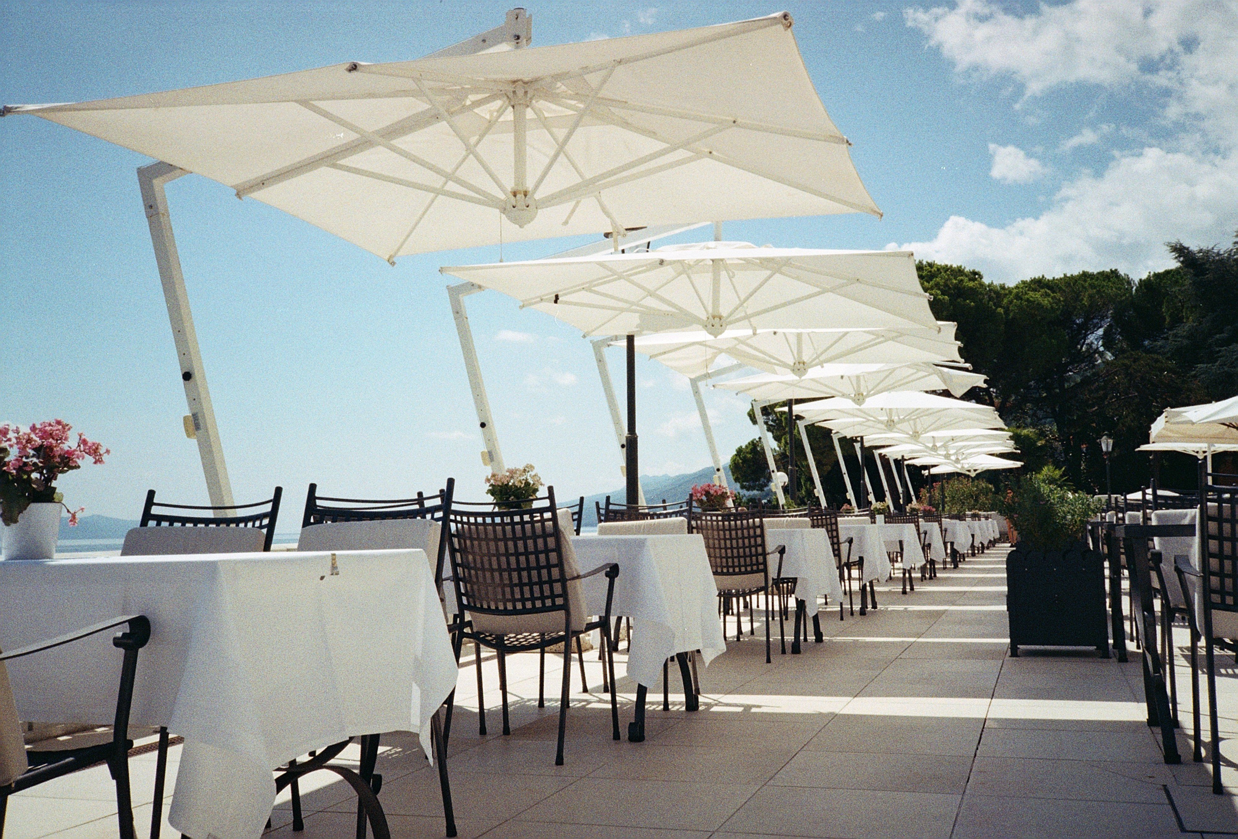 White umbrellas over linen-covered tables on a Mediterranean restaurant terrace