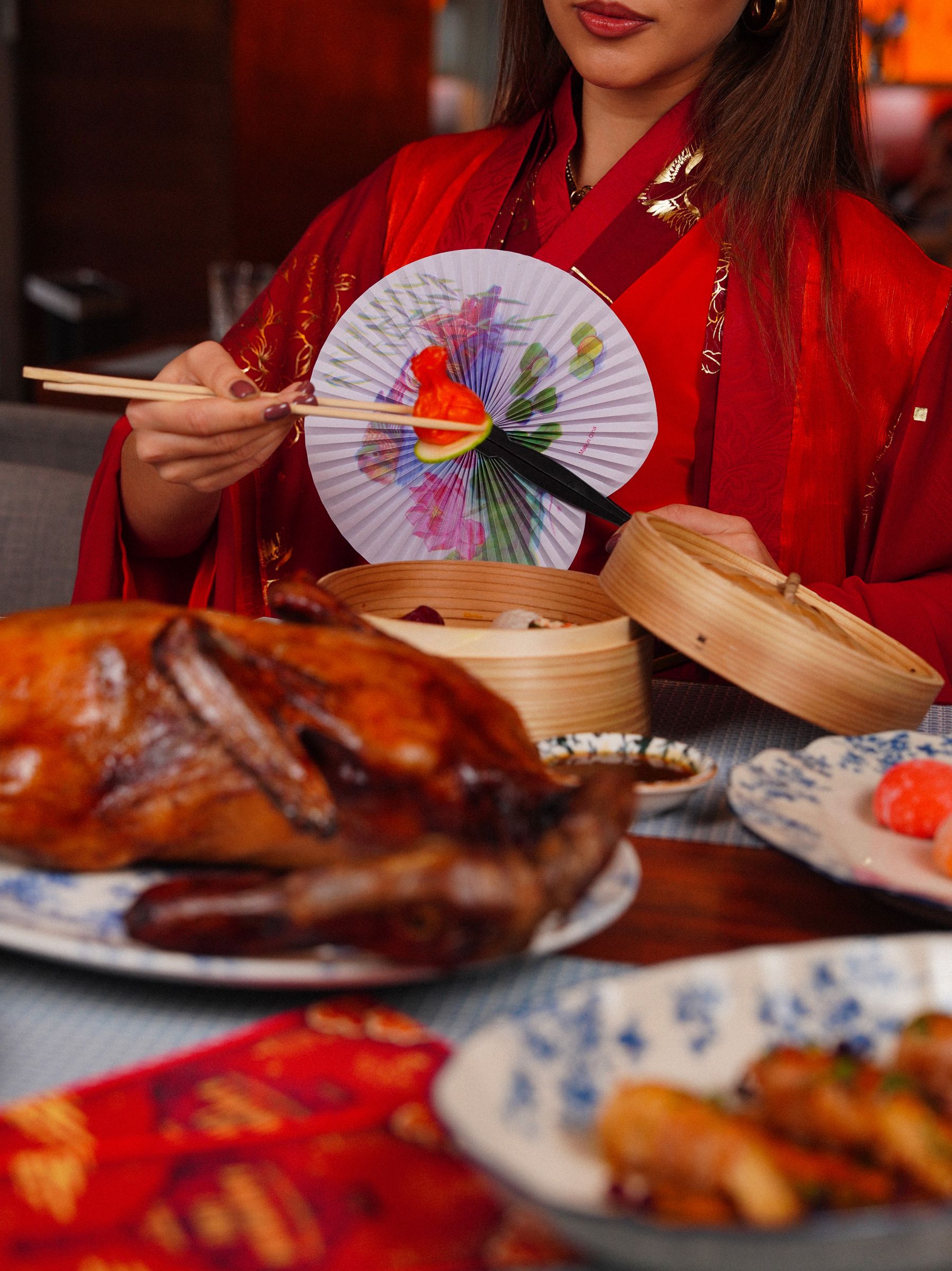 Whole roast Peking duck served on a table with dim sum baskets and side dishes