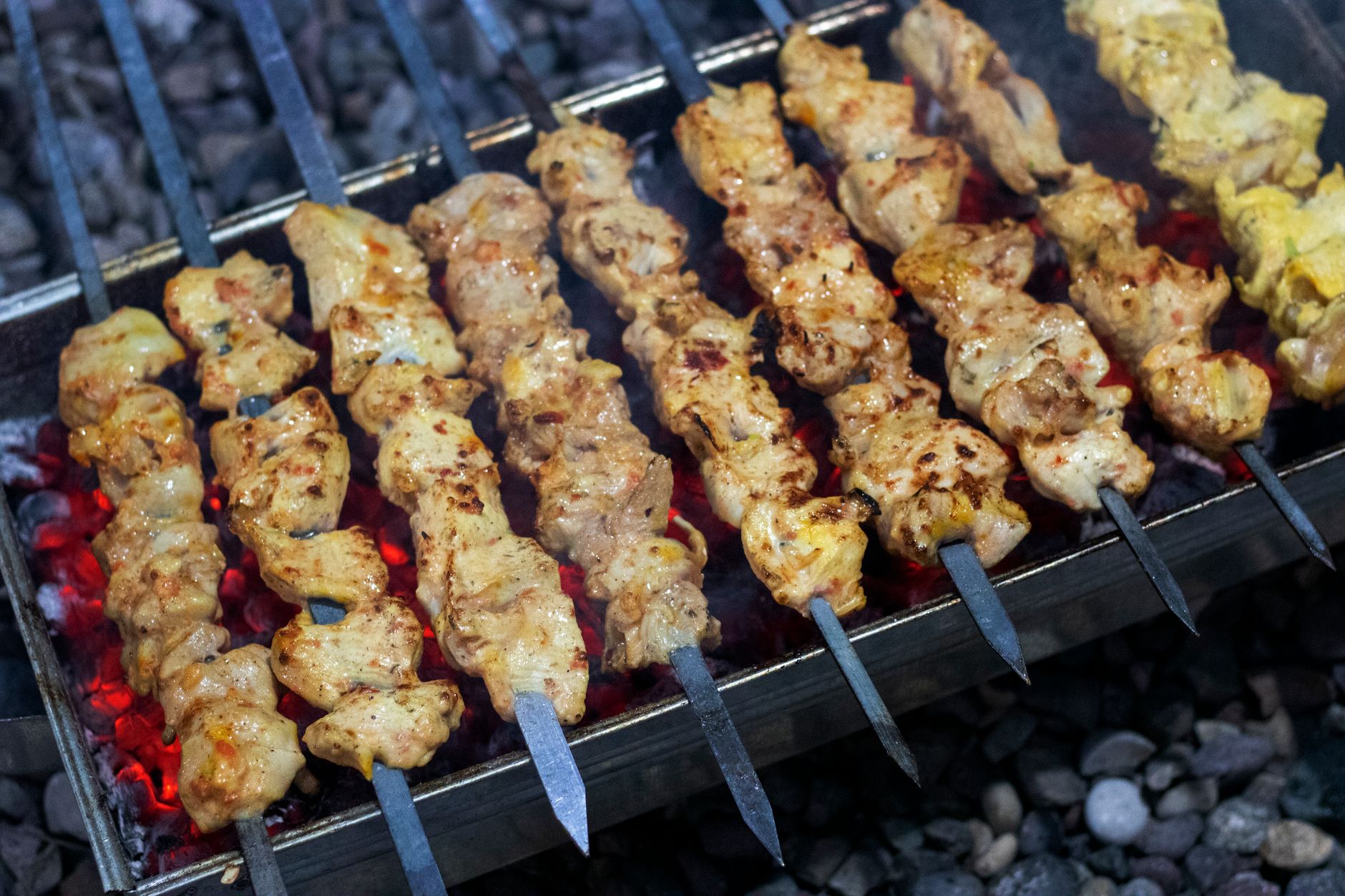 Skewers of marinated chicken kebab grilling over red-hot charcoal