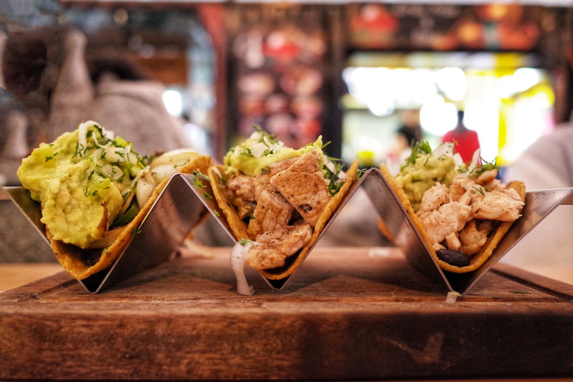 Weiche Tacos mit Guacamole und gegrilltem Hähnchen auf einem Holzbrett serviert
