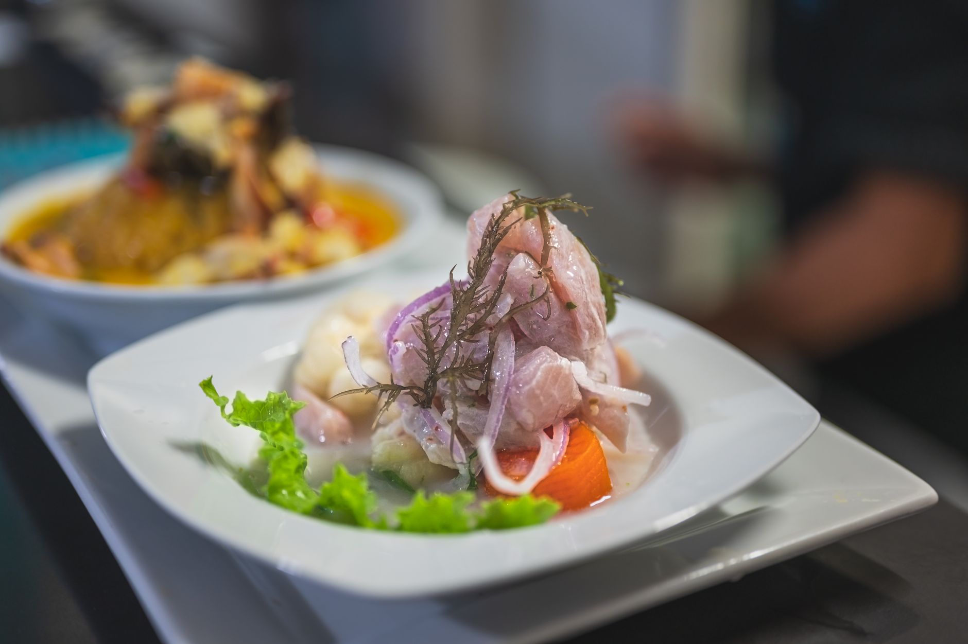 A plate of ceviche de anchoveta with red onion, chili, lettuce, corn and sweet potato