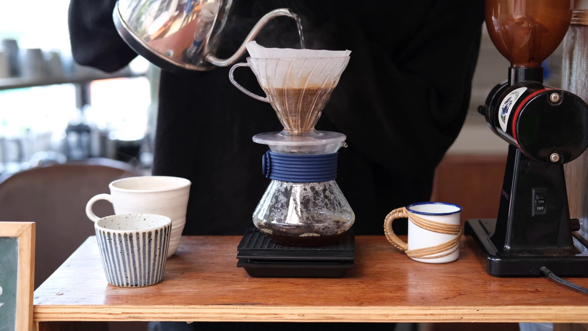 Mani che versano acqua calda su caffè macinato in un filtro pour-over
