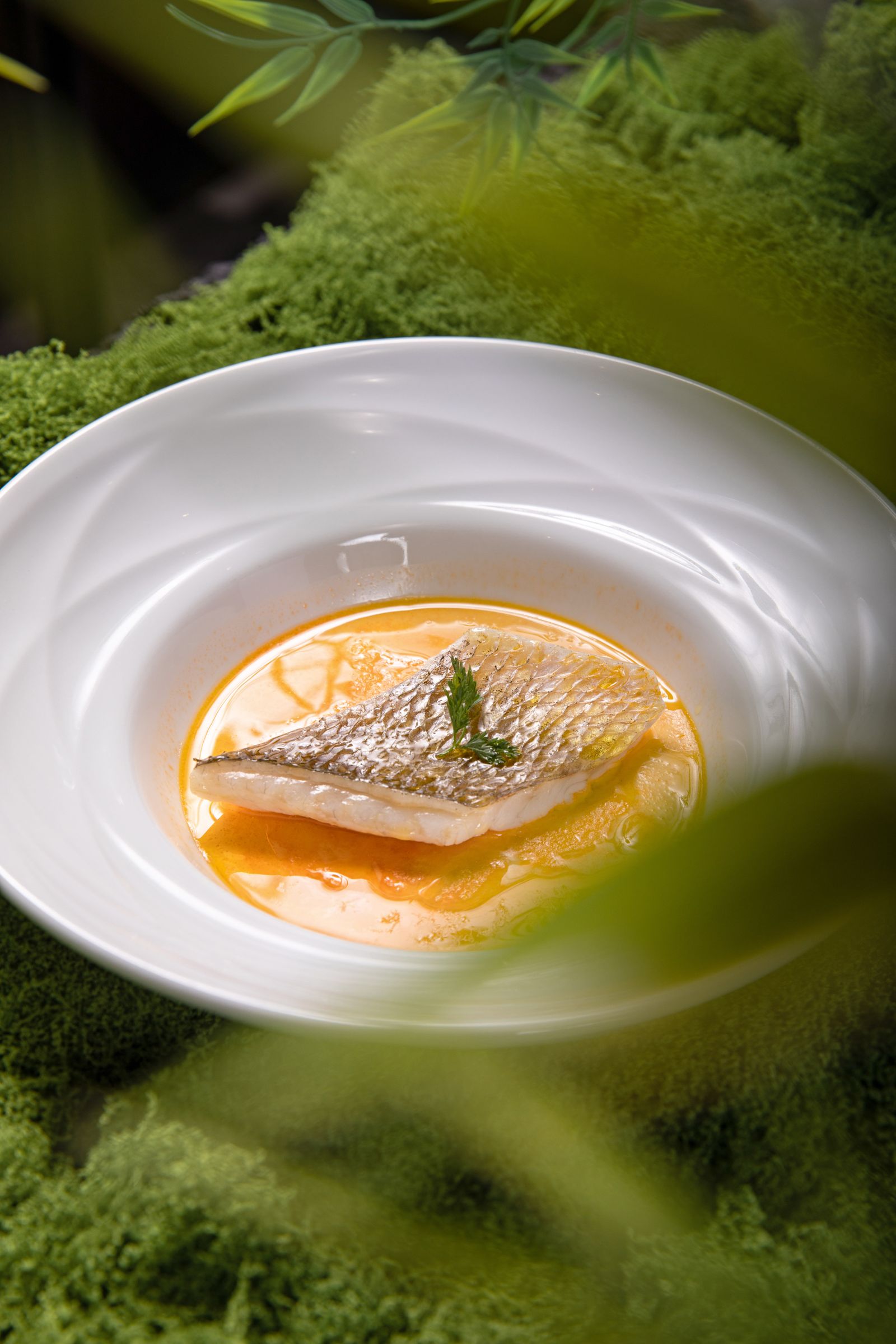 Un filetto di pesce scottato in padella con pelle croccante su una leggera salsa al burro e agrumi