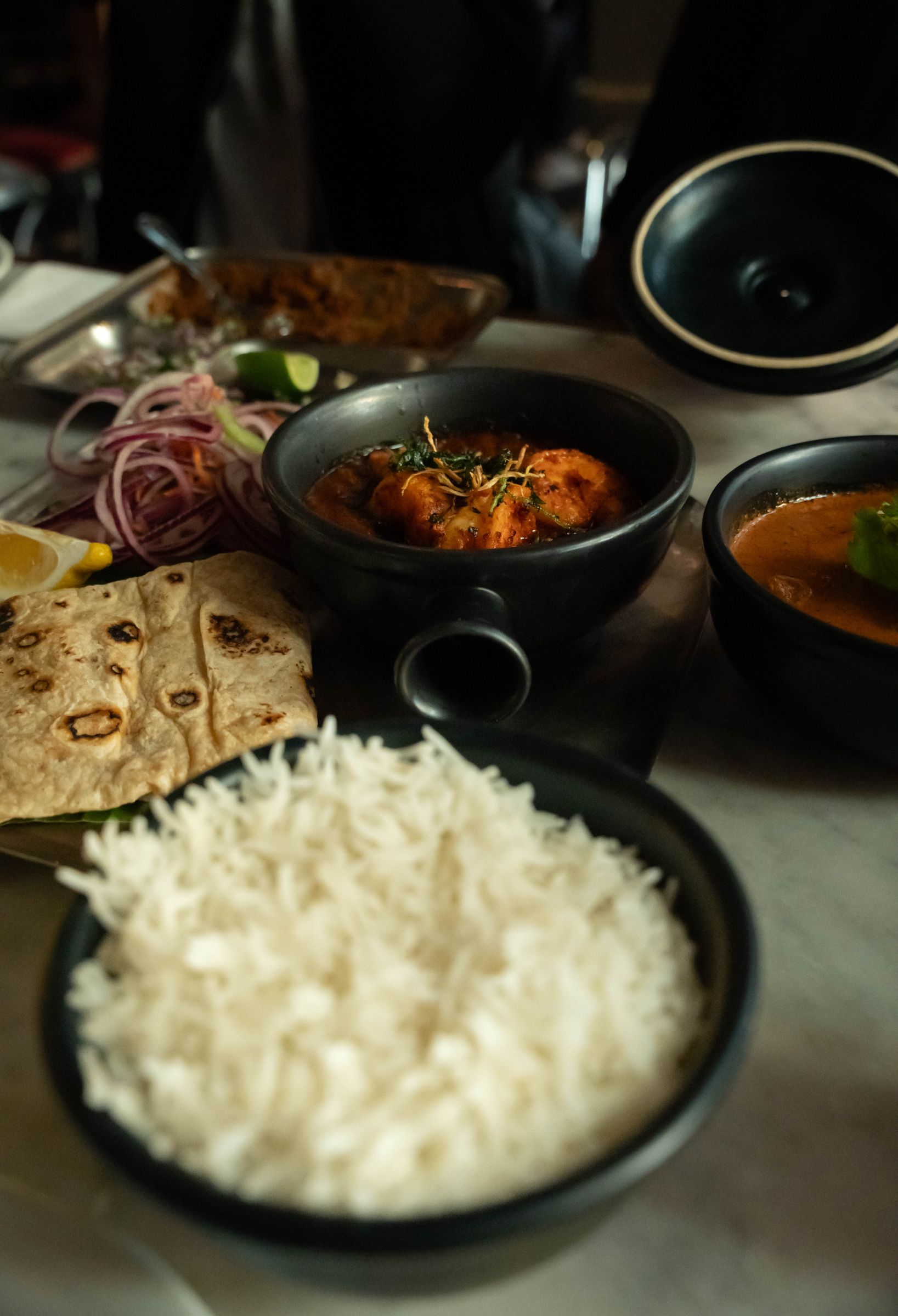 A spread of regional Indian dishes including curry, flatbread and rice on a restaurant table