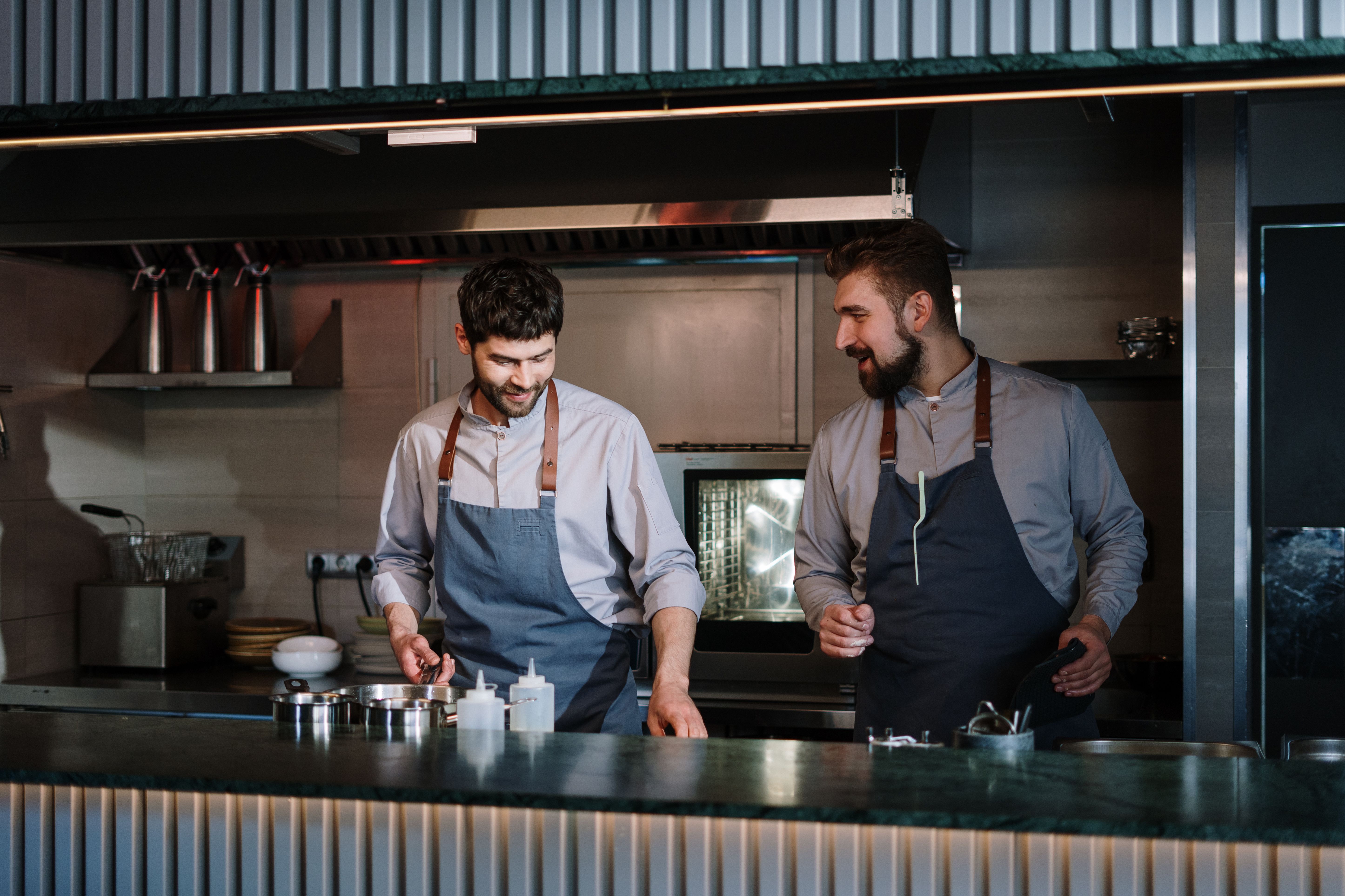 Two chefs in aprons prepare food together in a restaurant kitchen
