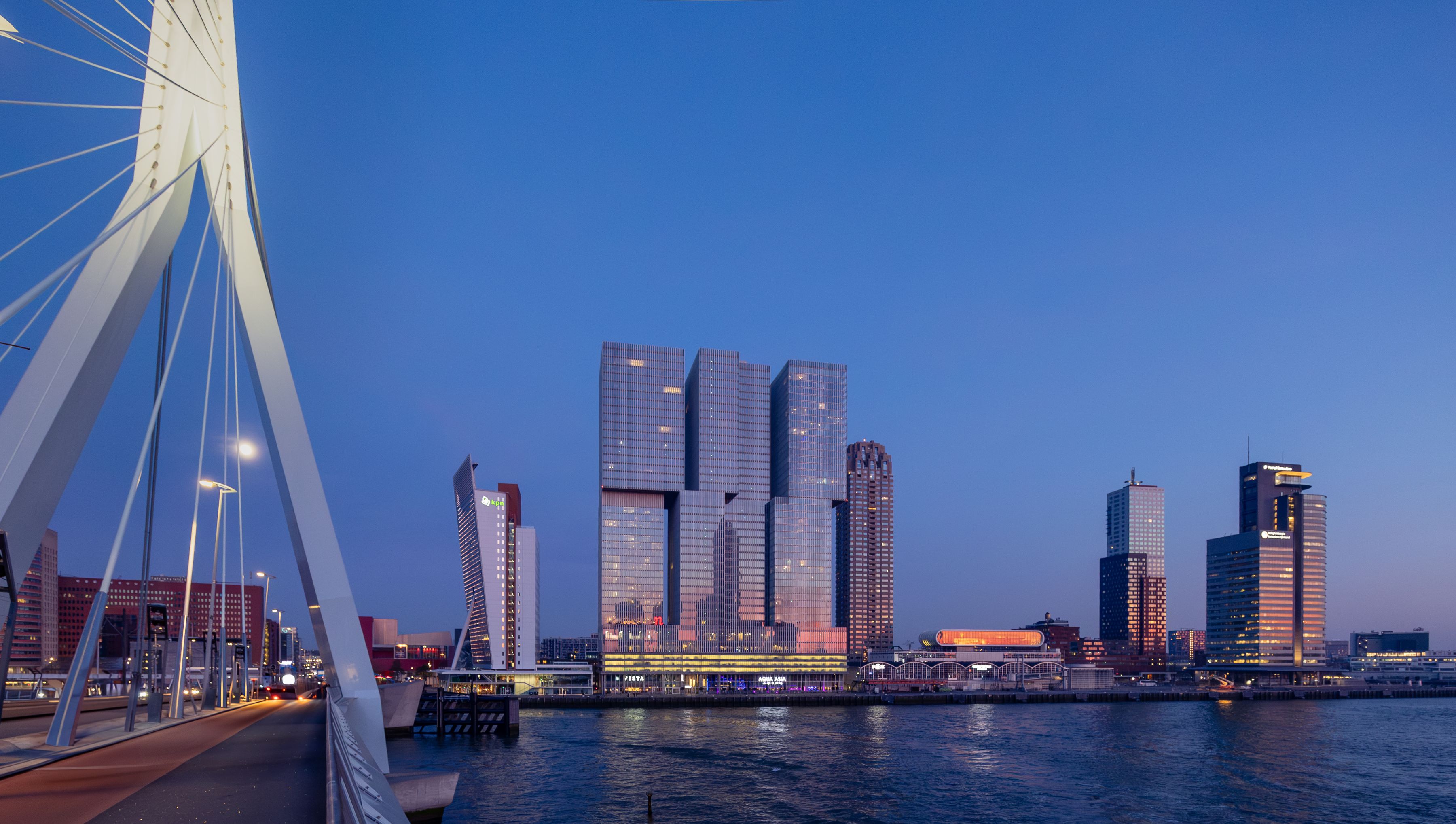Erasmus Bridge and the Rotterdam skyline lit up at dusk over the Nieuwe Maas