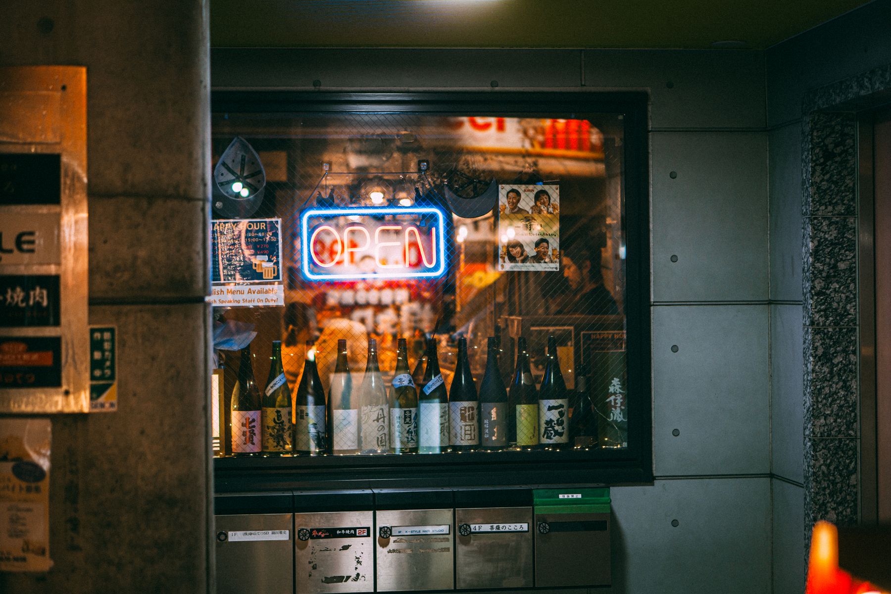 Sake and spirit bottles lined up in a neon lit Tokyo shop window