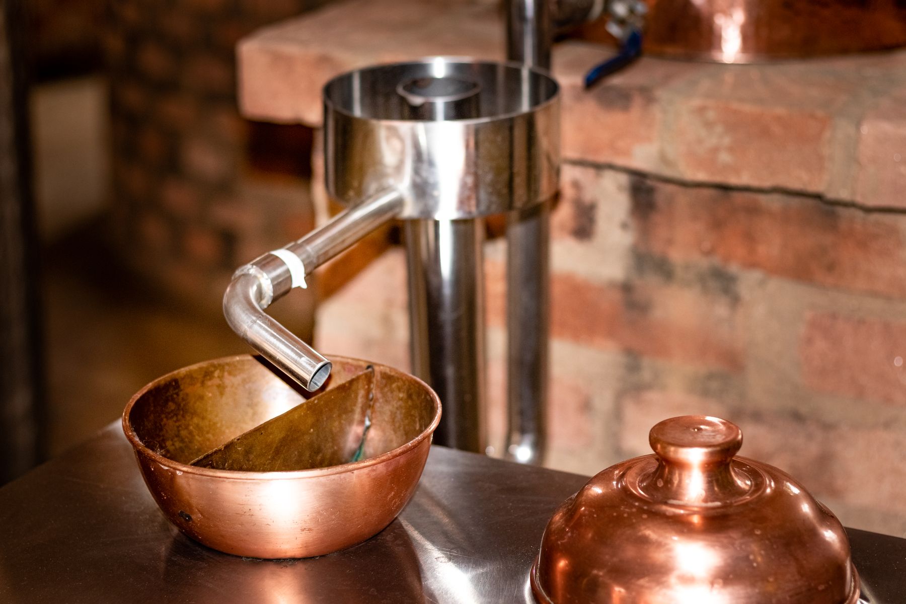 Récipients de distillation en cuivre et tuyau en acier devant un mur de briques