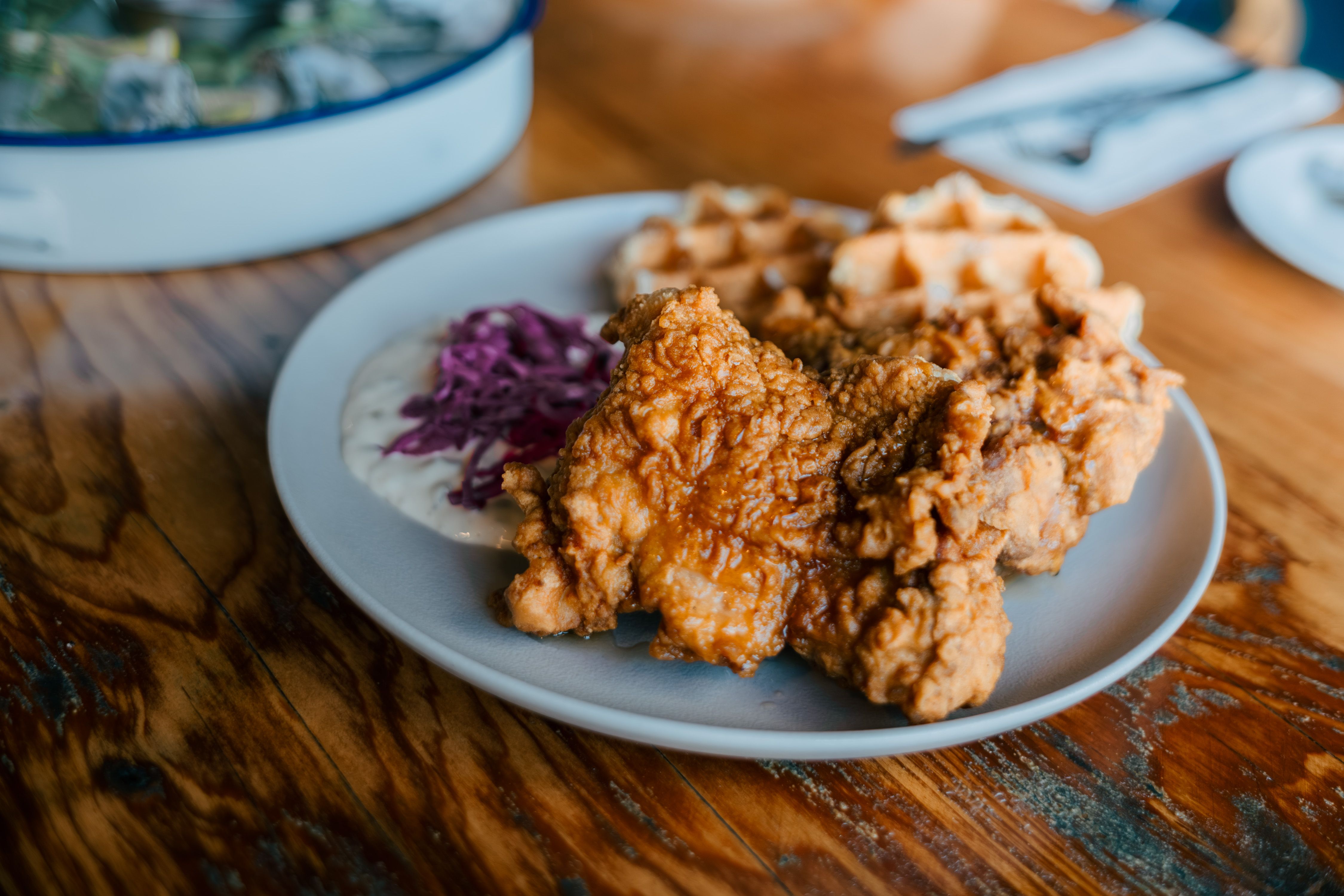 Plato de pollo frito con gofres sobre una mesa de madera